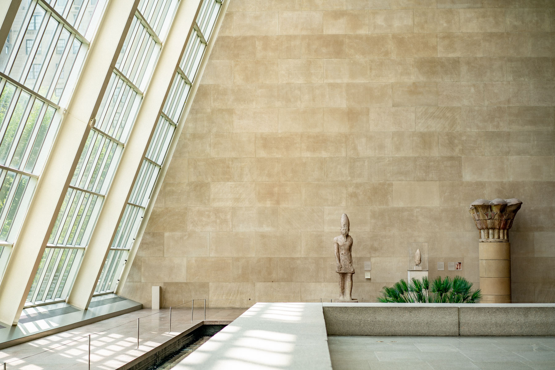 A stone statue stands in the Temple of Dendur wing at the Metropolitan Museum of Art.