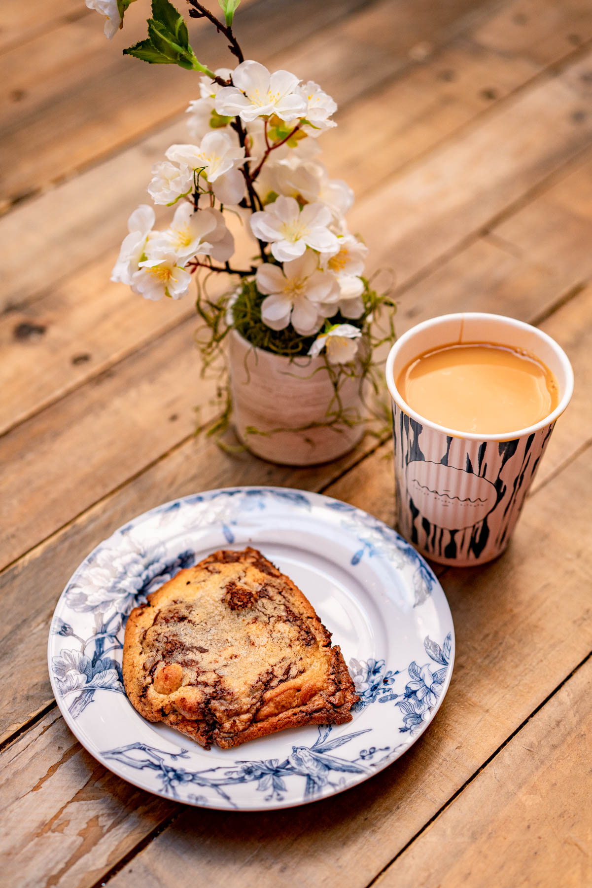 famous chocolate chip cookie from Maman and latte on a table with a plant as the centerpiece 