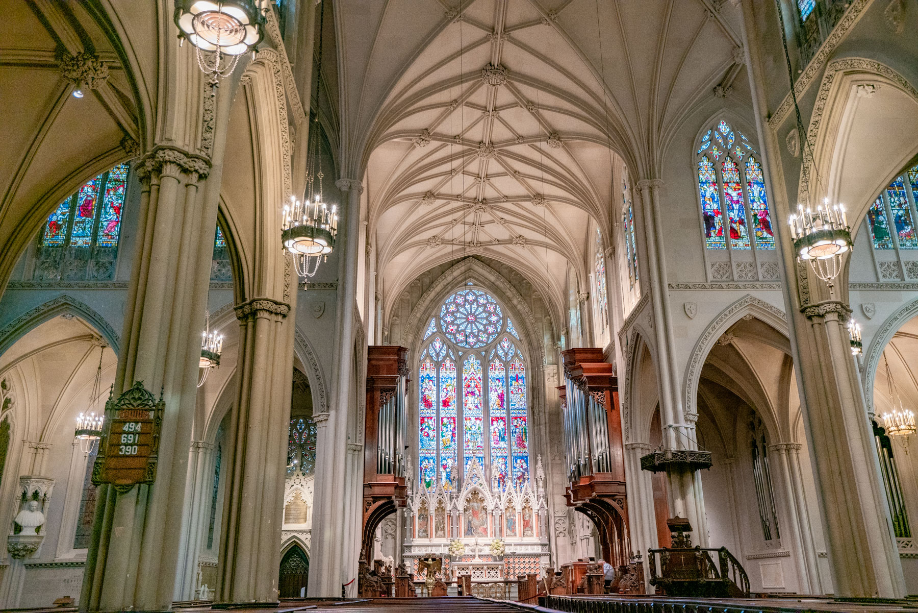 The Gothic Revival interior of a cathedral shows stained glass windows and vaulted ceilings.