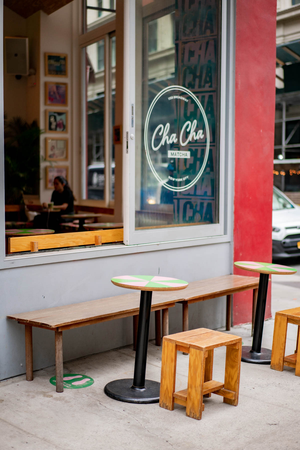 The storefront and outdoor seating of Cha Cha Matcha with tables and stools on the sidewalk.