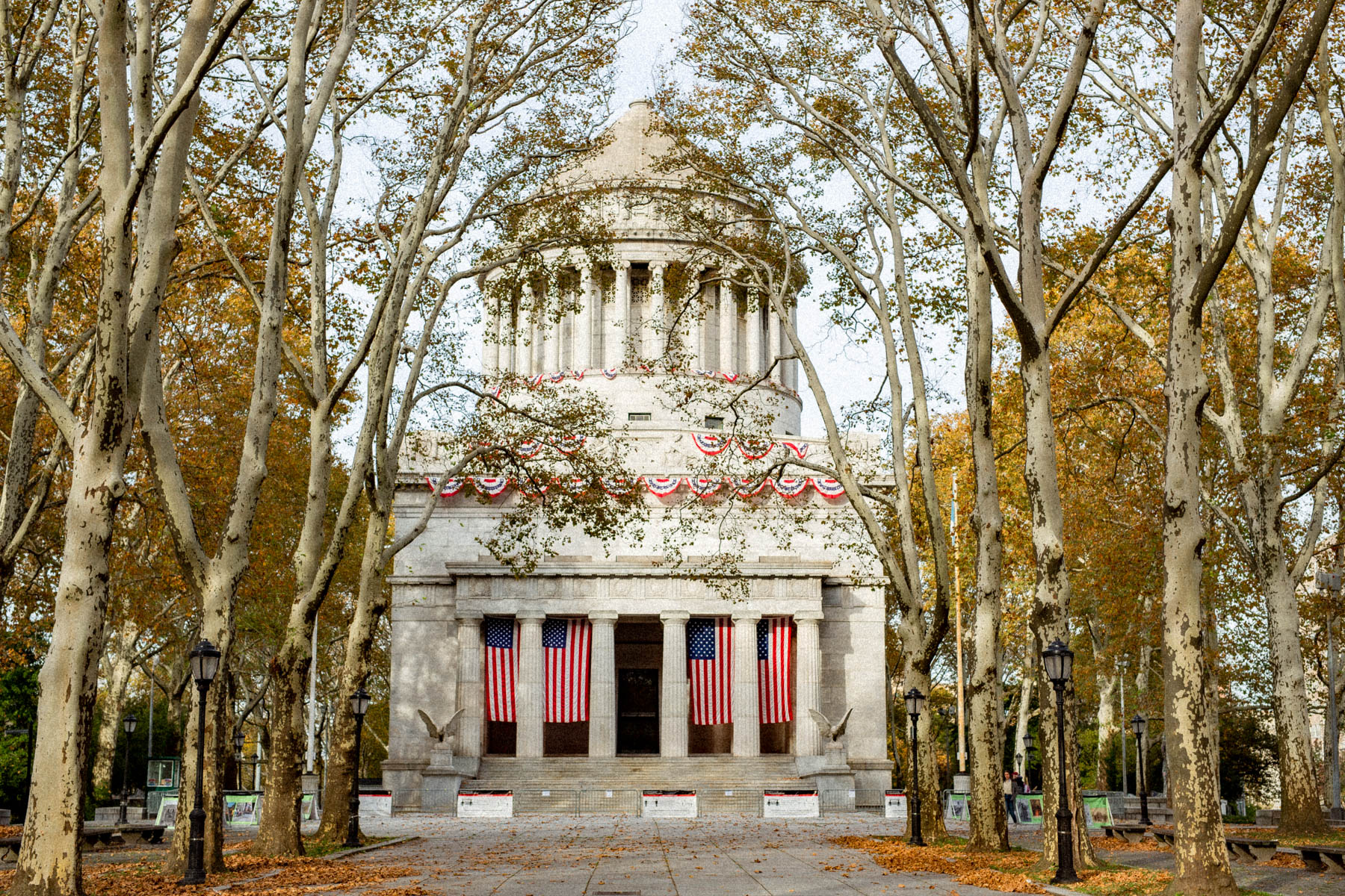 Grant's Tomb is framed by bare autumn trees with American flags draped across its columns.