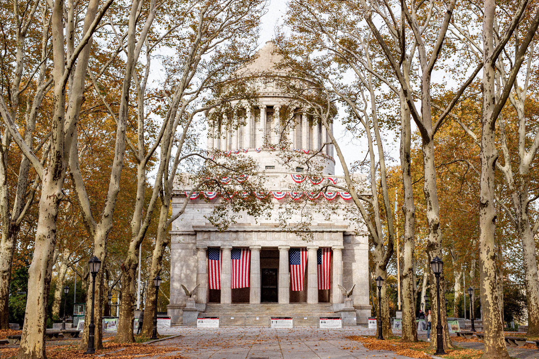 Grant's Tomb monument is framed by bare autumn trees with American flags hung across its columns.