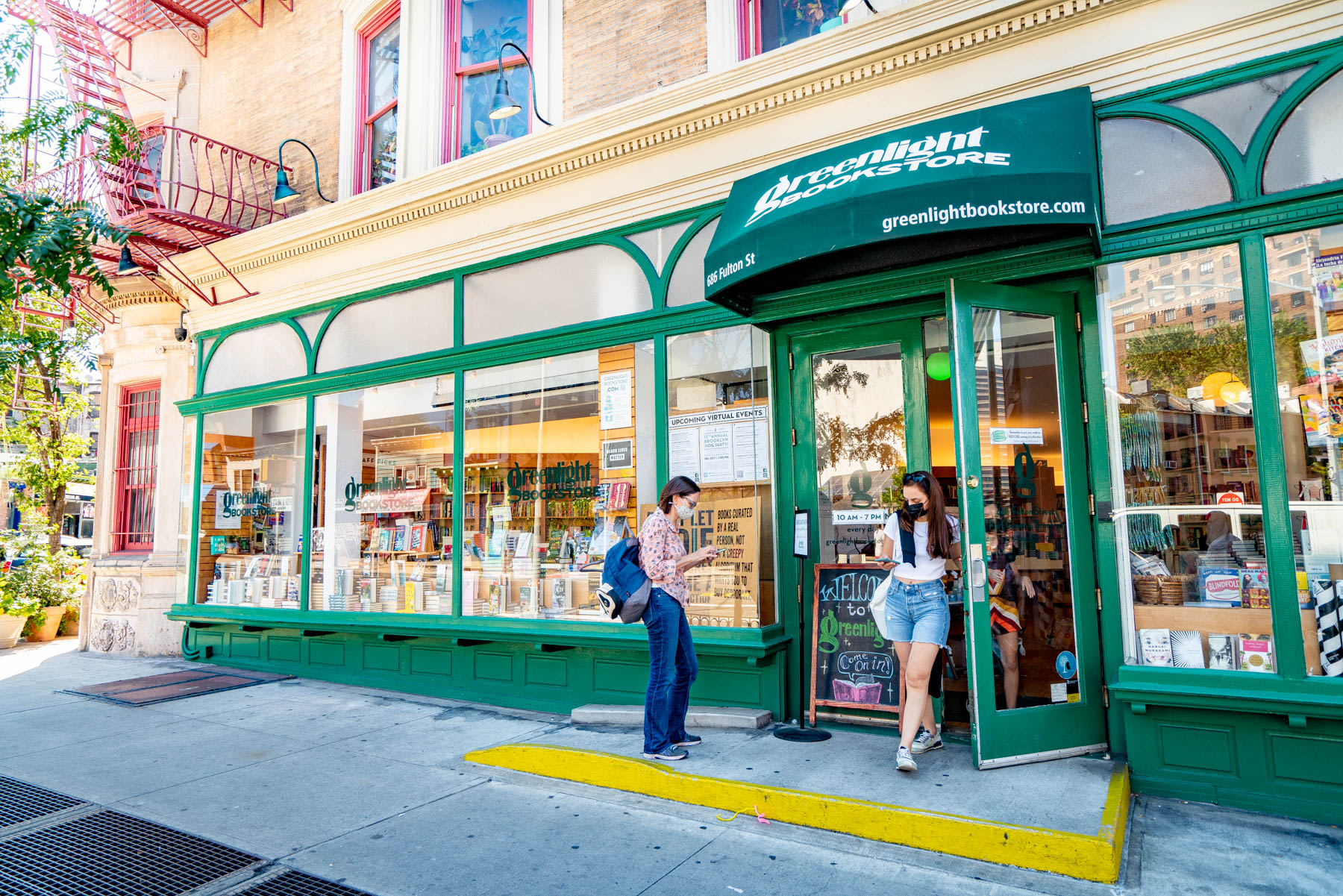 People stand outside the storefront of Greenlight Bookstore on Fulton Street.