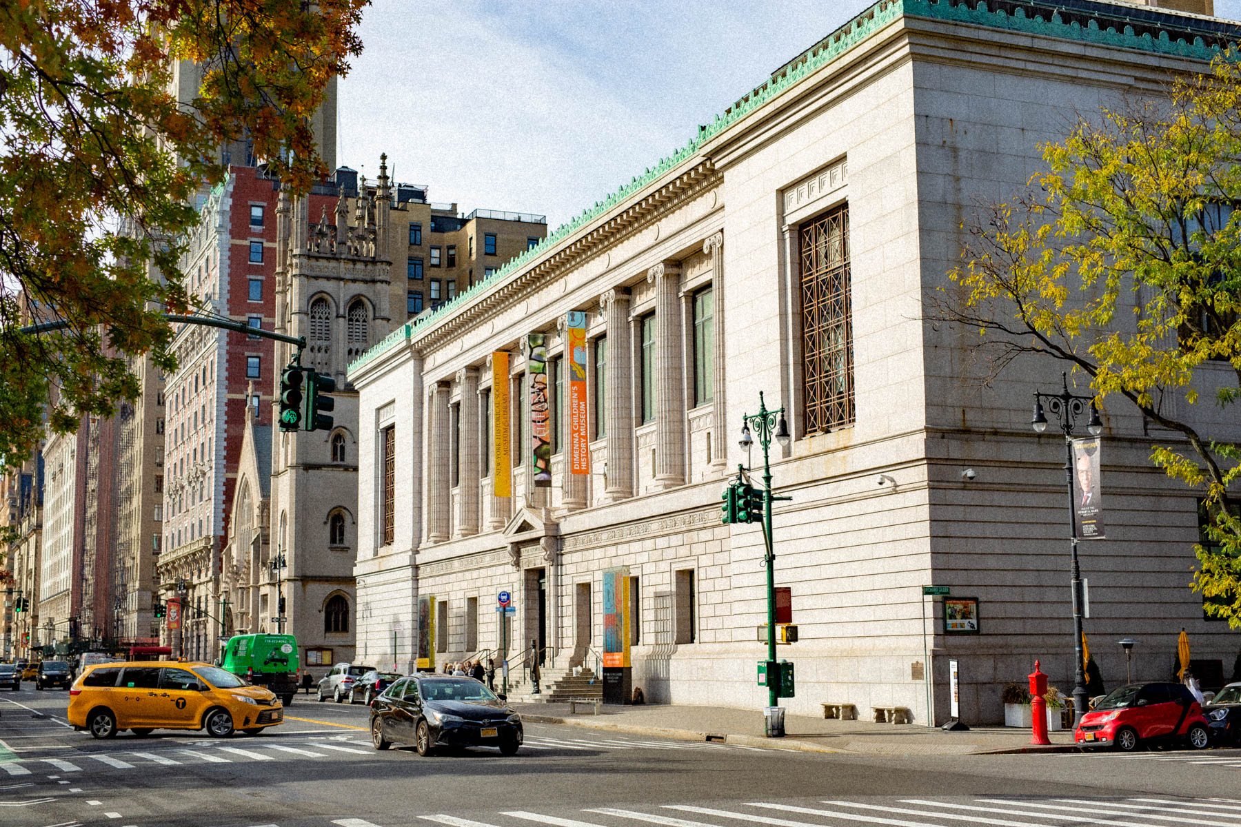 The New-York Historical Society building stands on Central Park West with a taxi passing by.