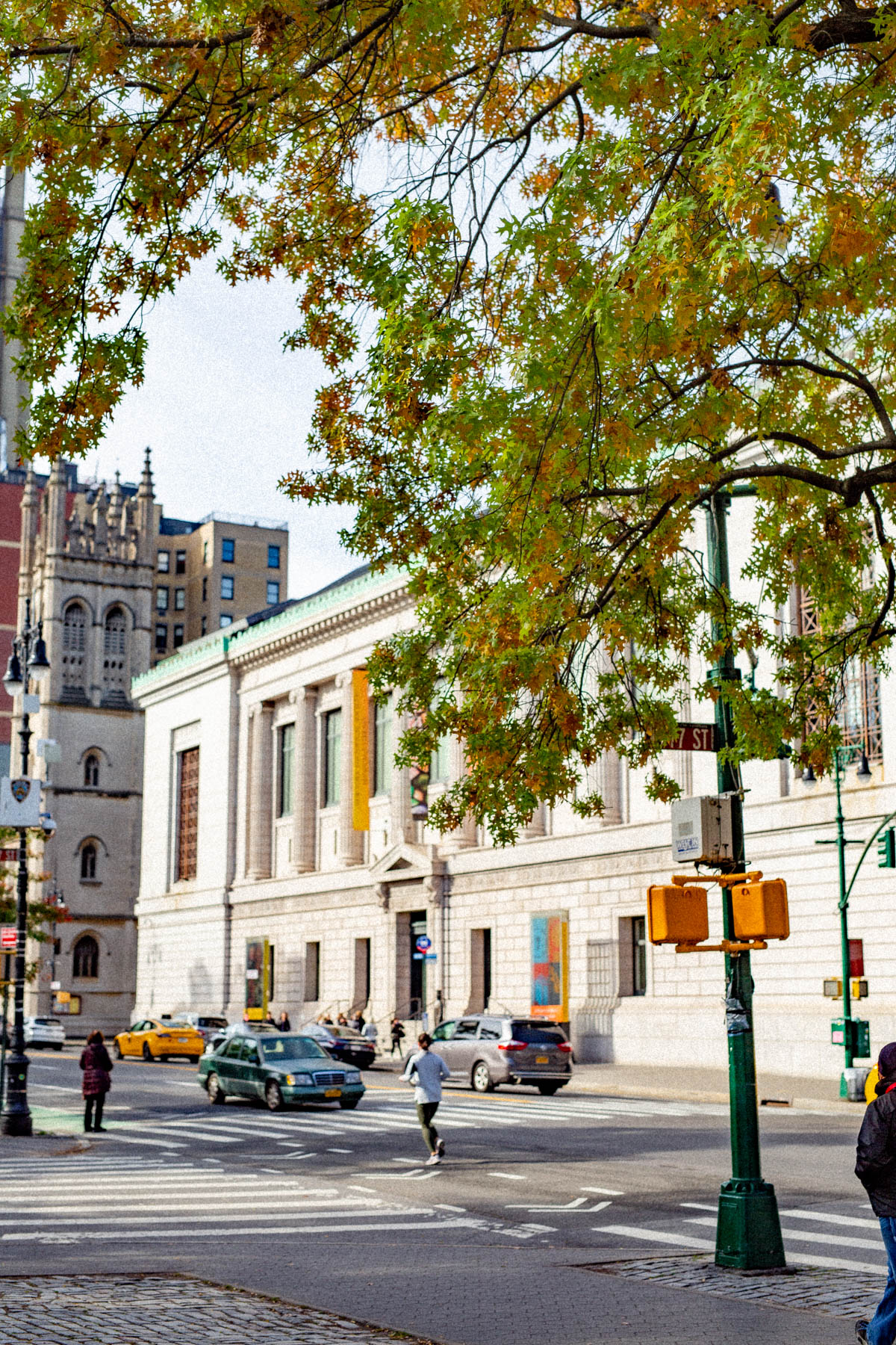 A street corner view of the New-York Historical Society building with autumn trees overhead.