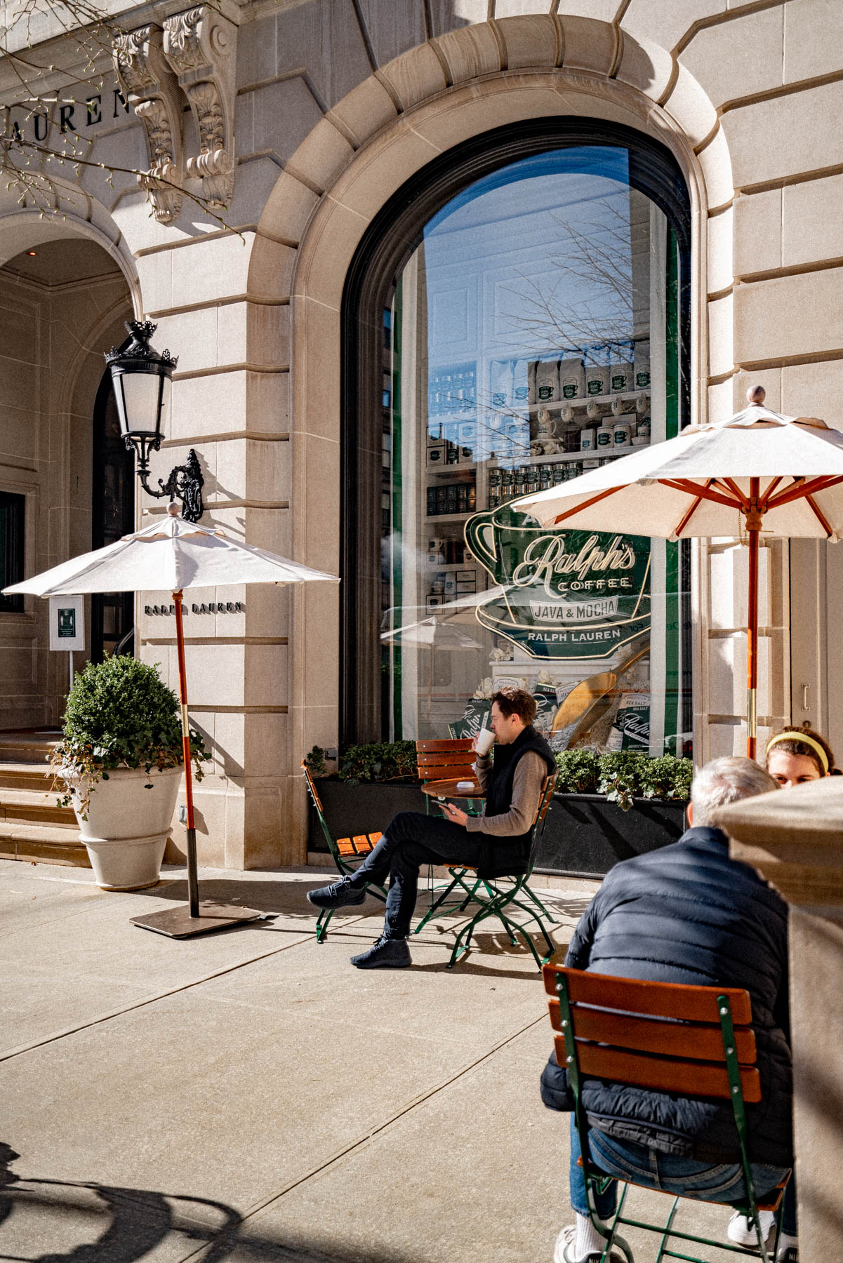 People sit at outdoor tables in front of Ralph's Coffee at Ralph Lauren's West Village storefront.