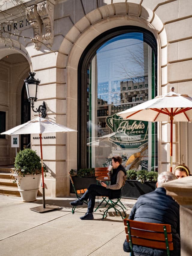 People sit at outdoor tables in front of Ralph's Coffee at Ralph Lauren's storefront.