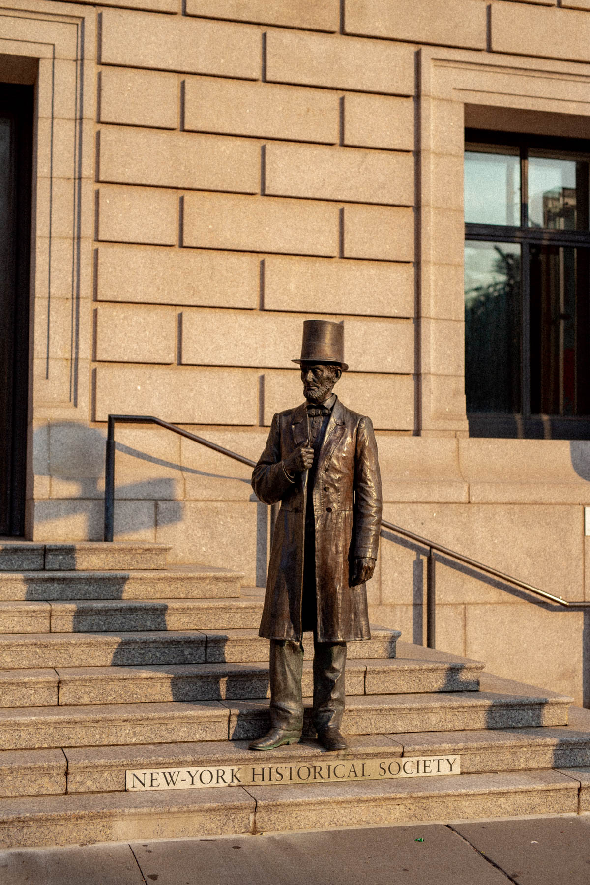 A bronze statue of Abraham Lincoln stands on the steps of the New-York Historical Society.