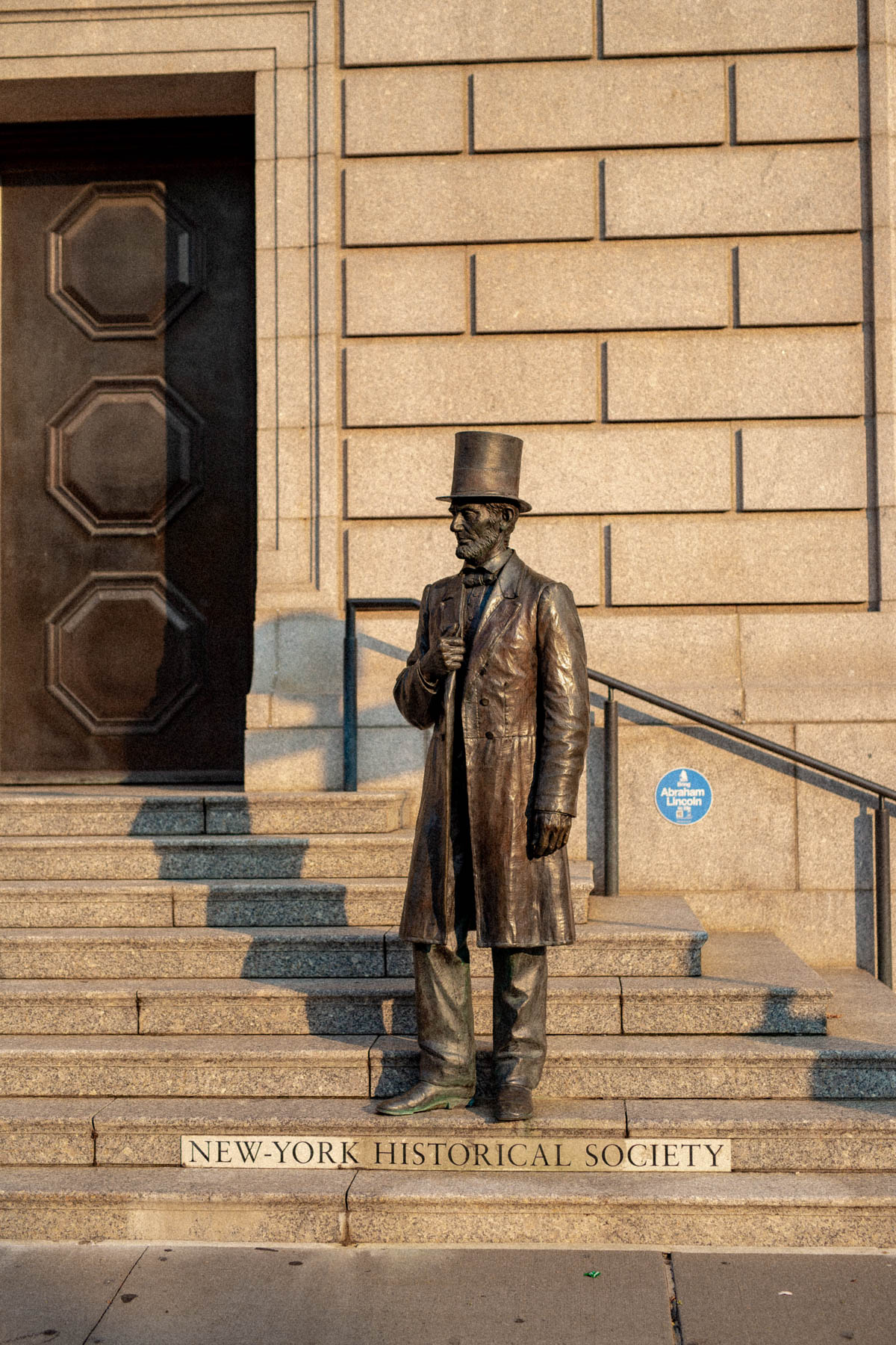 A bronze statue of Abraham Lincoln stands on the entrance steps of the New-York Historical Society.