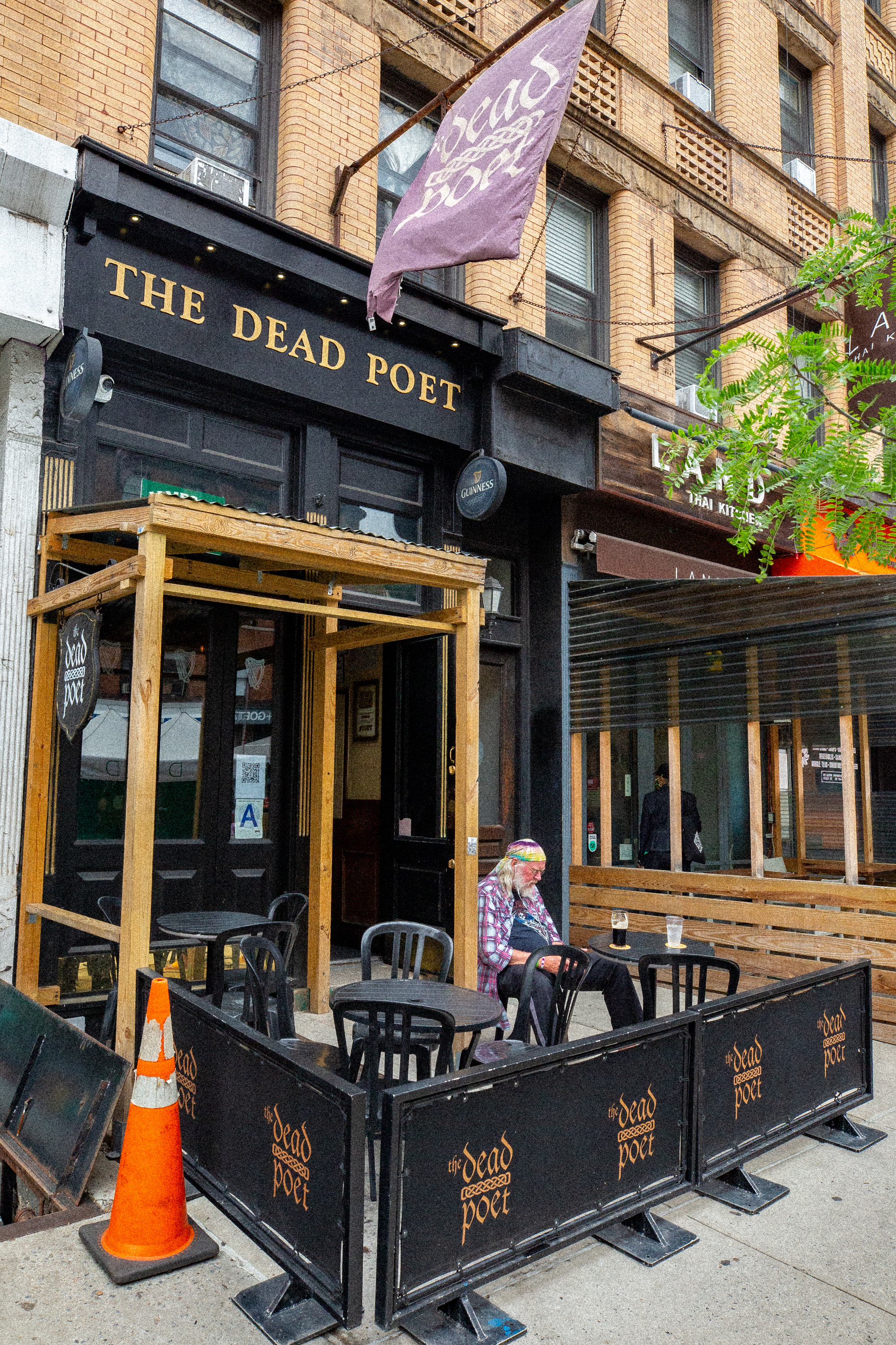 A person sits outside The Dead Poet bar on the Upper West Side