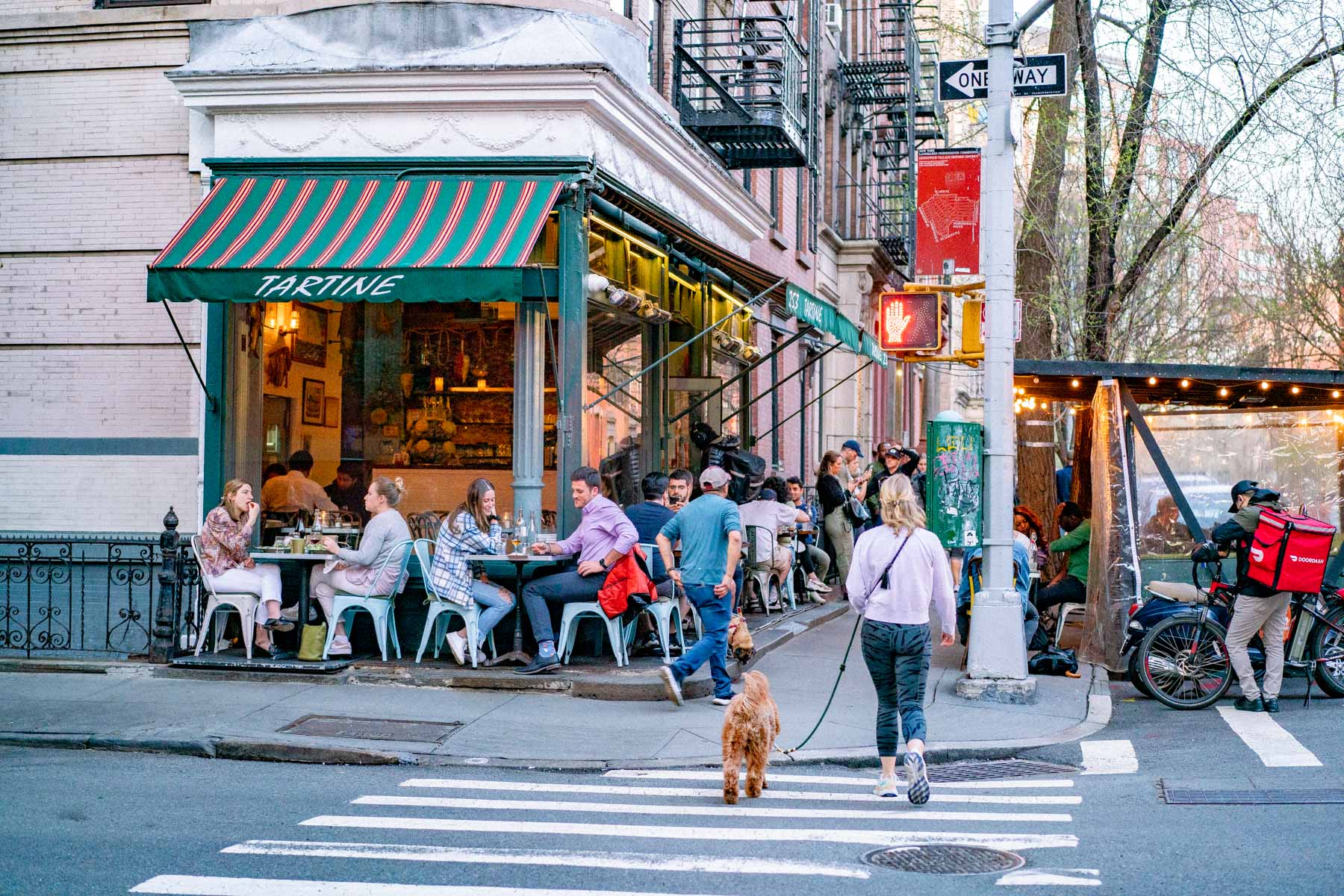 Diners sit at outdoor tables in front of Tartine restaurant on a West Village corner.