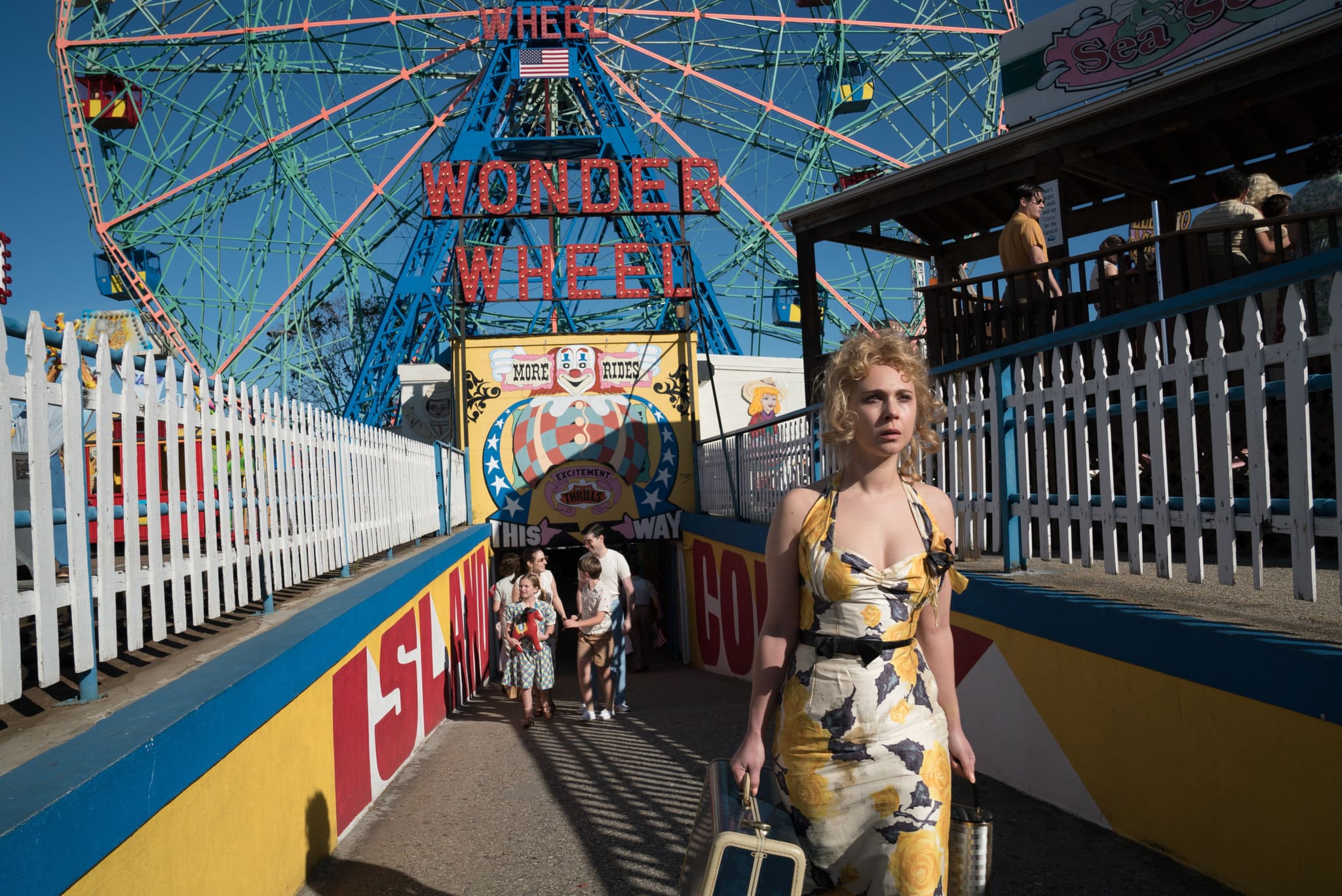 A woman in a vintage floral dress walks past the Wonder Wheel entrance at Coney Island.