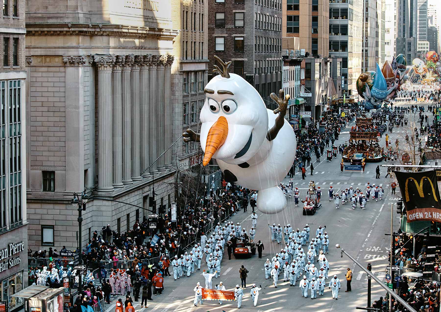 An Olaf balloon floats above crowds along the Macy's Thanksgiving Day Parade route.
