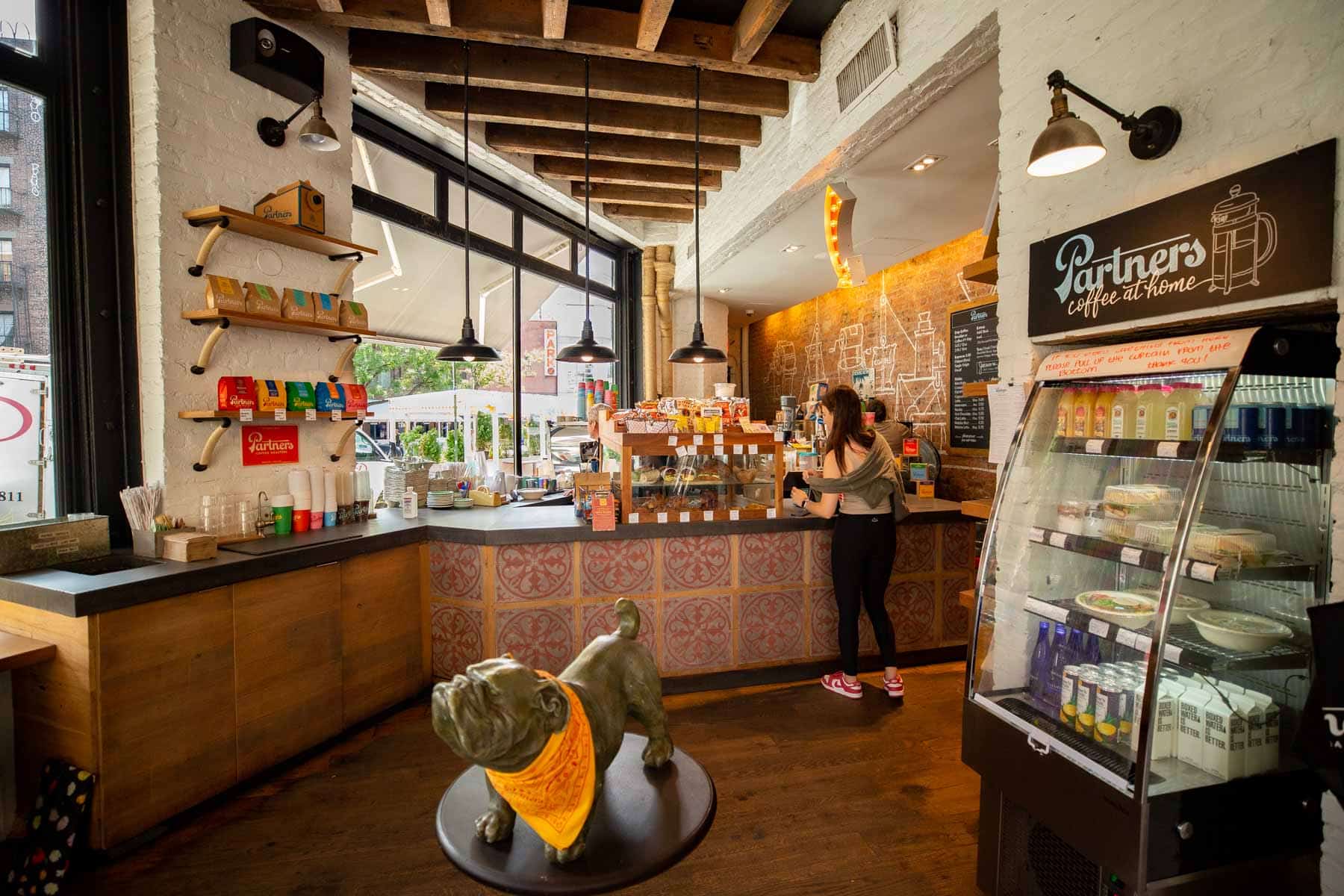 Interior of a coffee shop with a bulldog statue and customers at the counter.