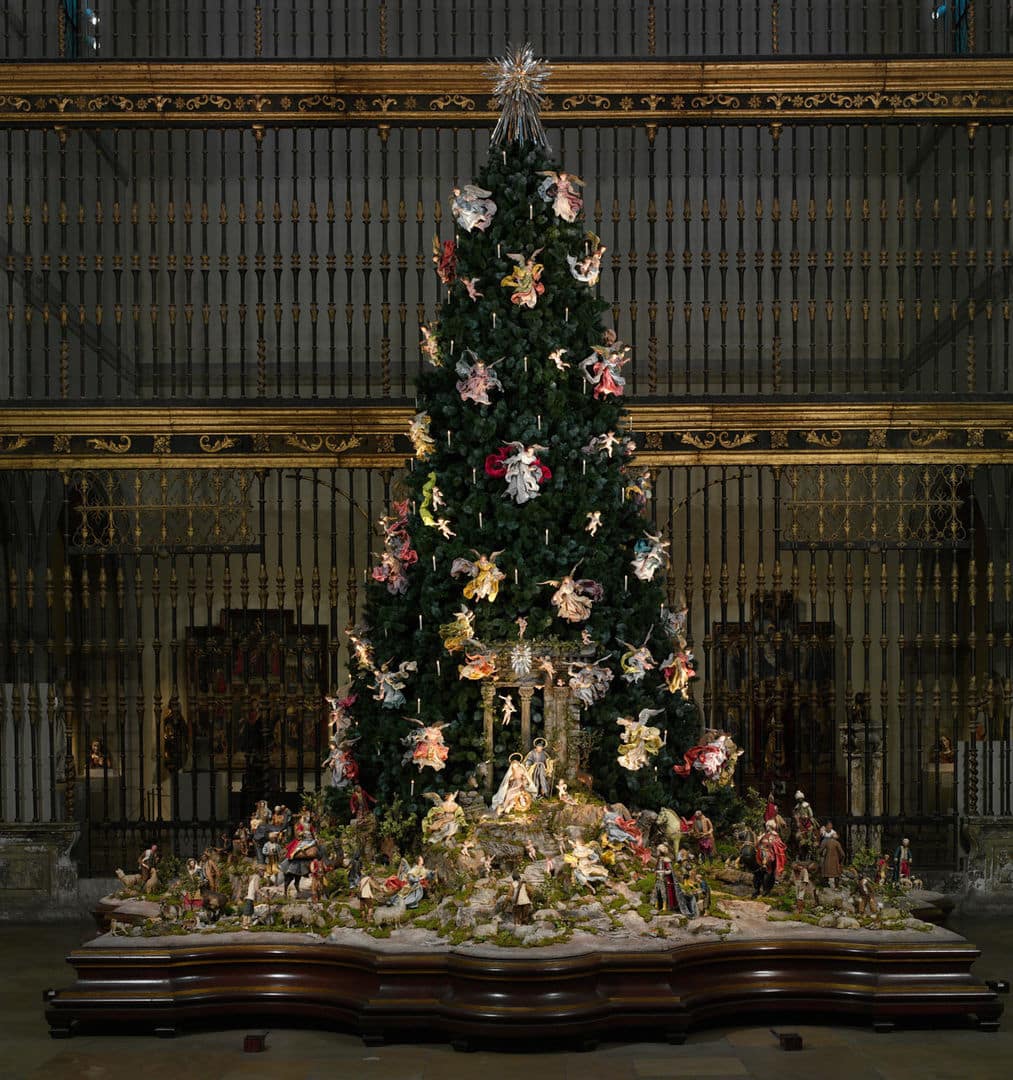 The Metropolitan Museum's Neapolitan Baroque Christmas tree and creche display stands before an ornate iron gate.