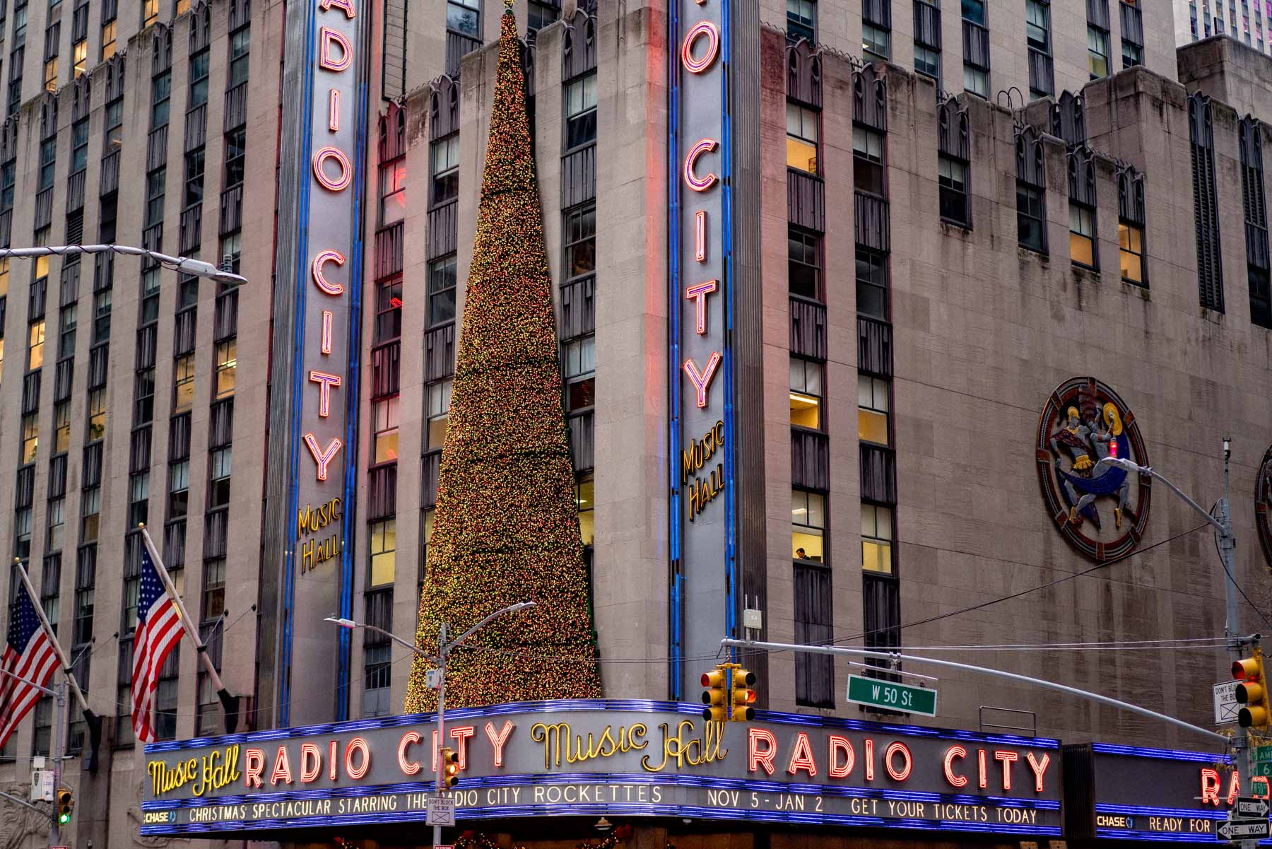 Radio City Music Hall marquee decorated with a Christmas tree and neon signage.