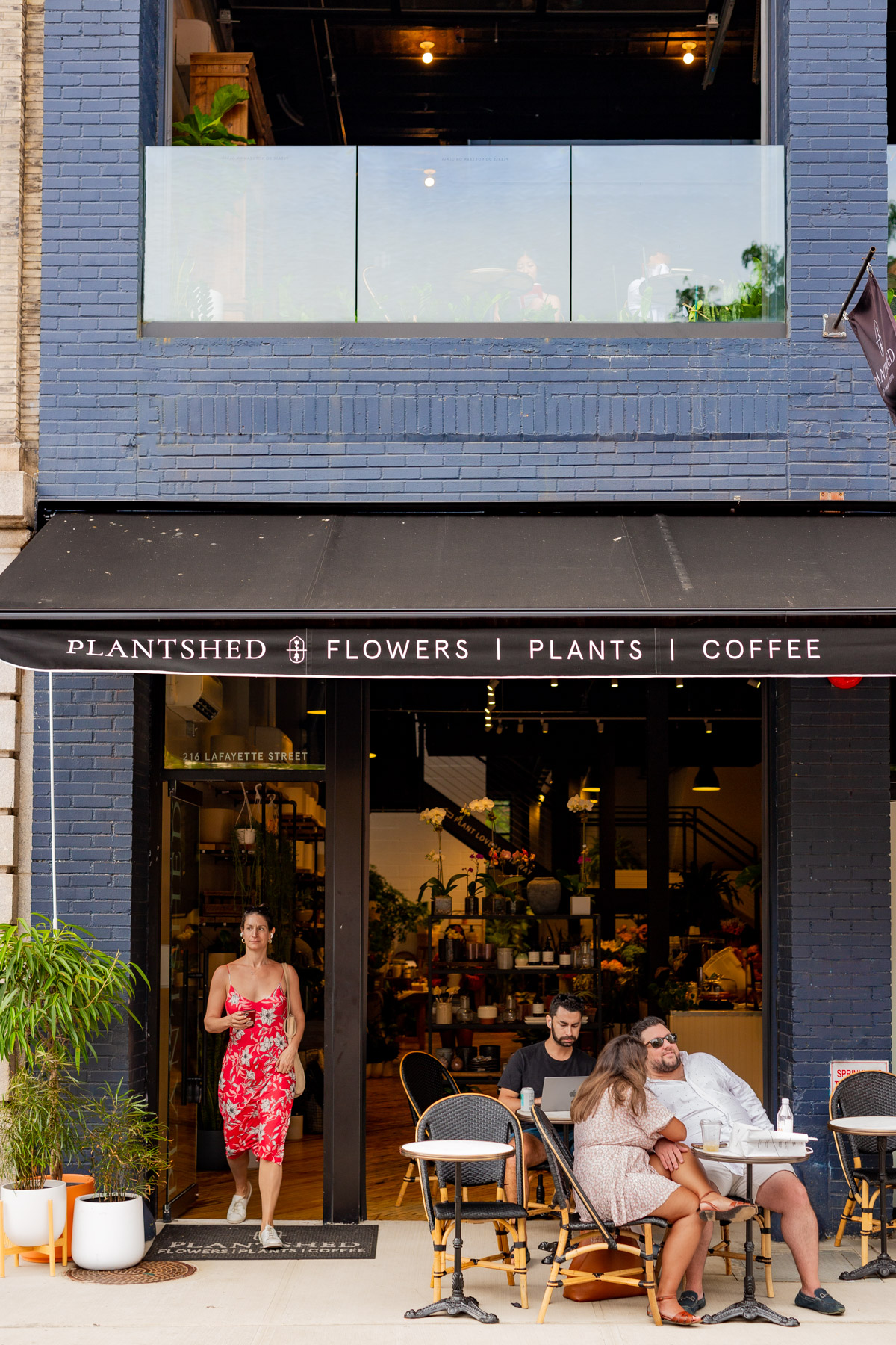 People sit outside the Plantshed flower and coffee shop storefront in SoHo.