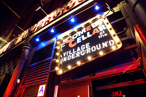 A lit marquee sign reads The Comedy Cellar at the Village Underground at night.