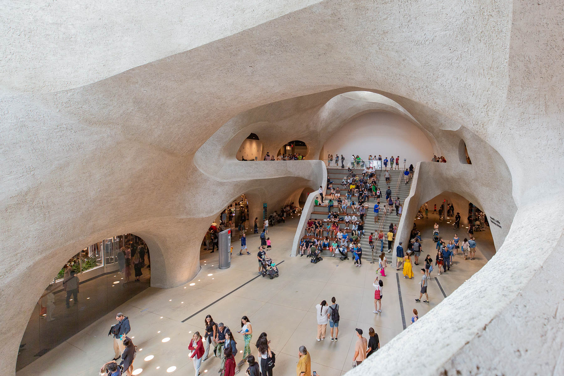 Visitors move through the cave-like white atrium of the American Museum of Natural History's new wing.