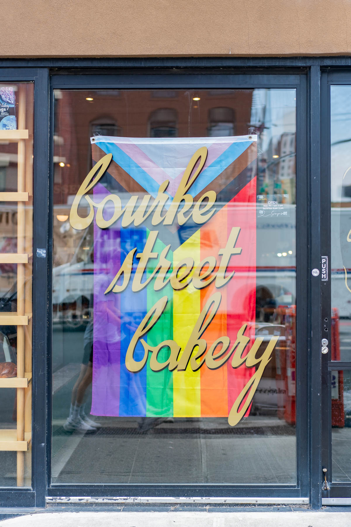 A pride flag hangs in the glass door of Bourke Street Bakery in Chelsea.