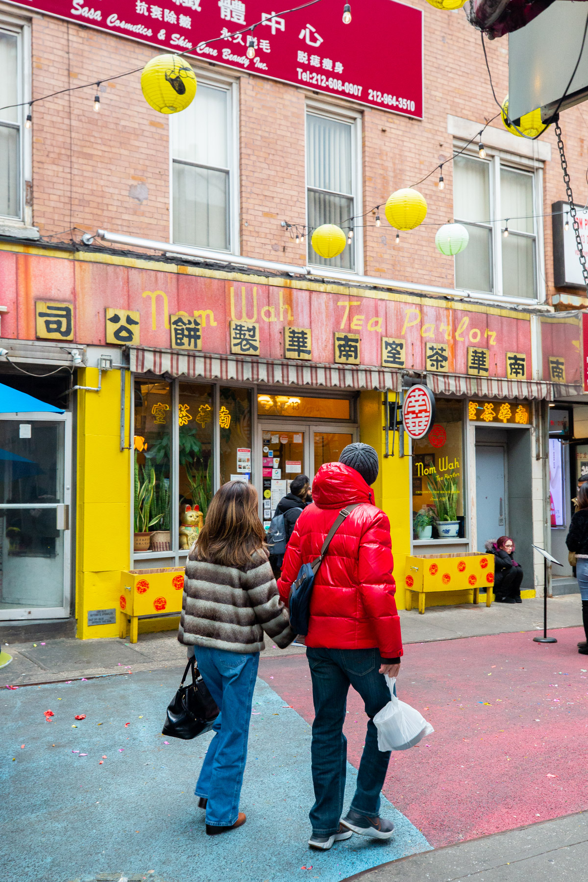People walk past the Nom Wah Tea Parlor storefront during a Lunar New Year parade in Chinatown.