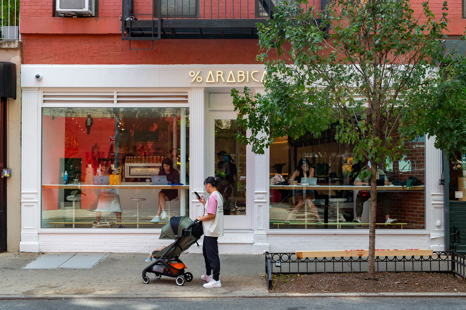 A woman with a stroller pauses outside the % Arabica coffee shop storefront on the Lower East Side.