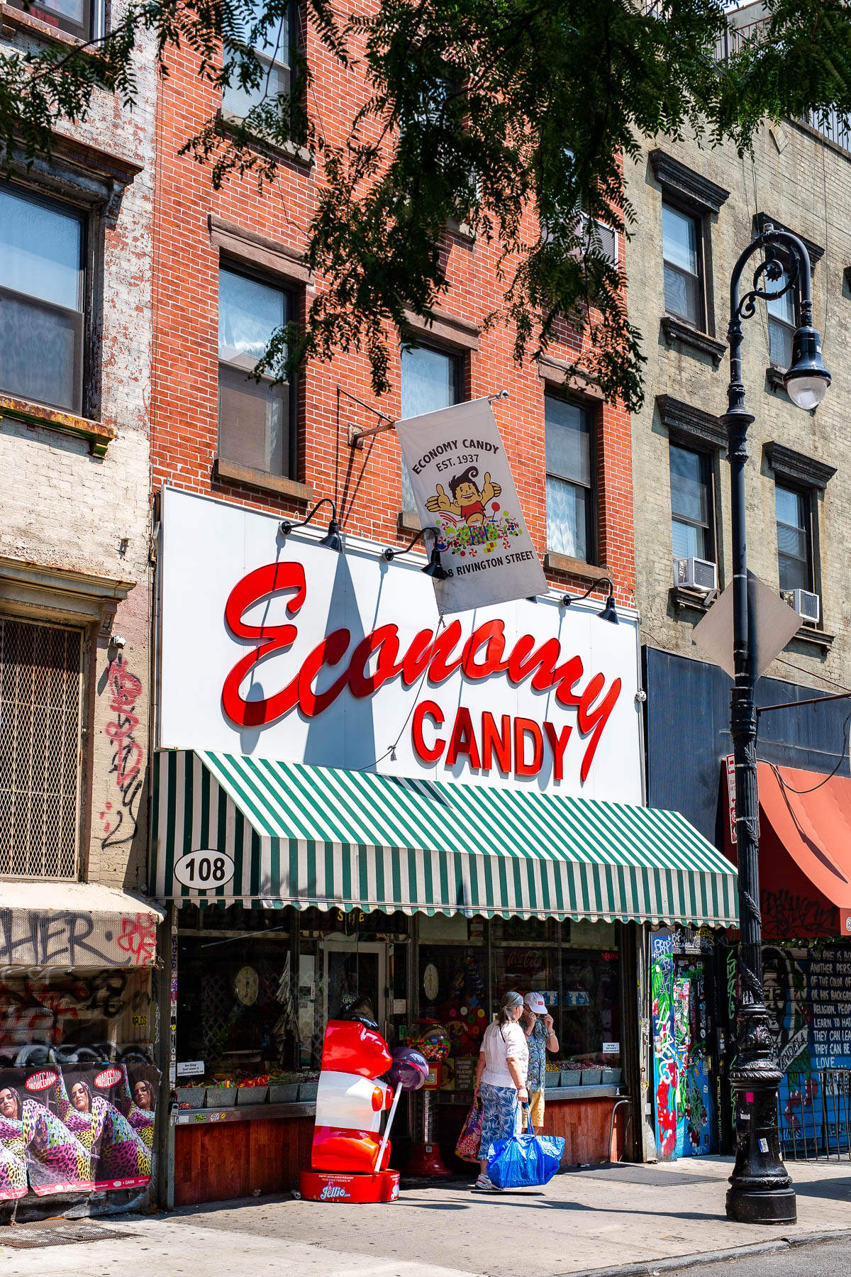 A storefront view of Economy Candy on Rivington Street with two pedestrians outside.