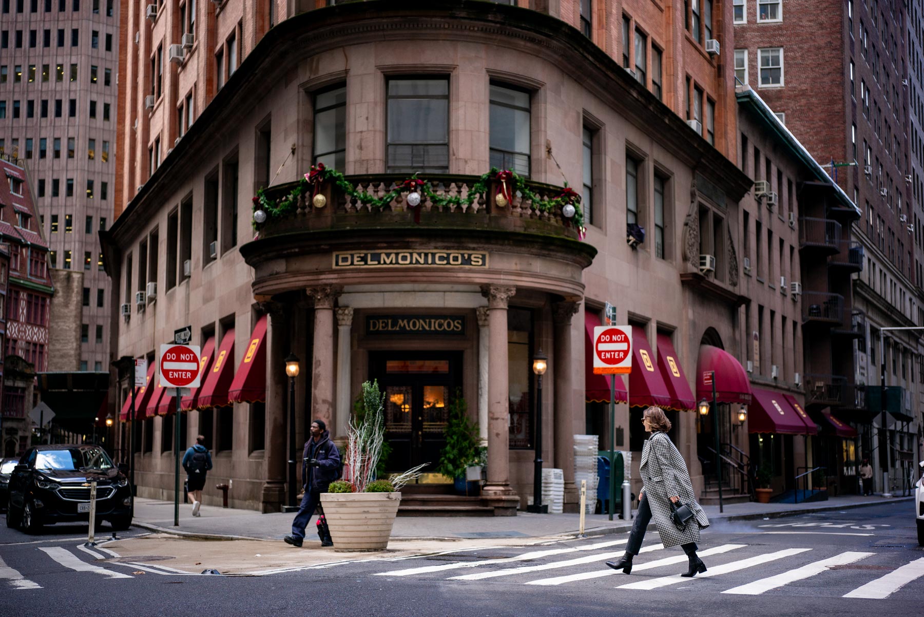 A woman crosses the street in front of the historic Delmonico's restaurant building.