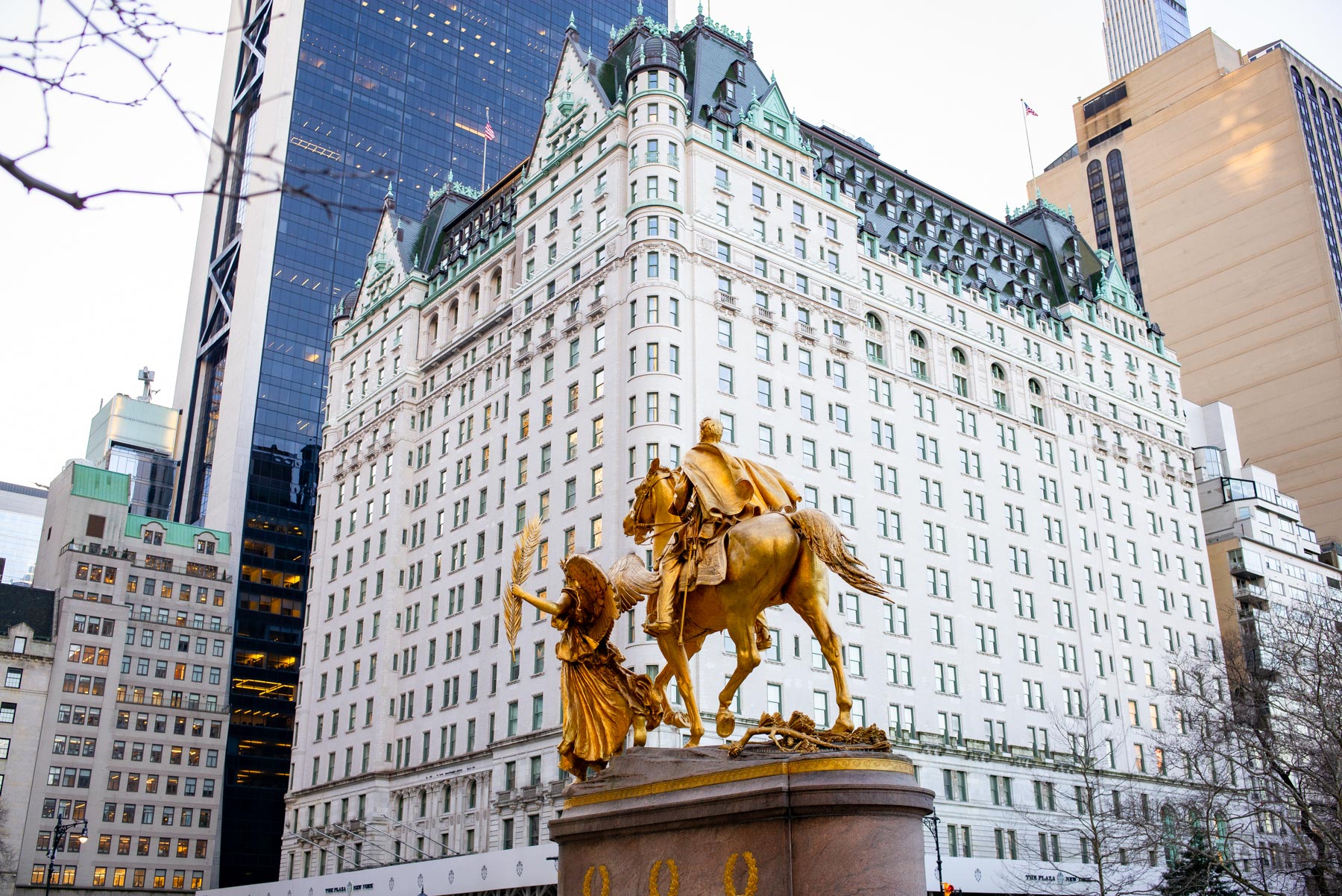 The Plaza Hotel rises behind the gilded Sherman Monument statue in winter.