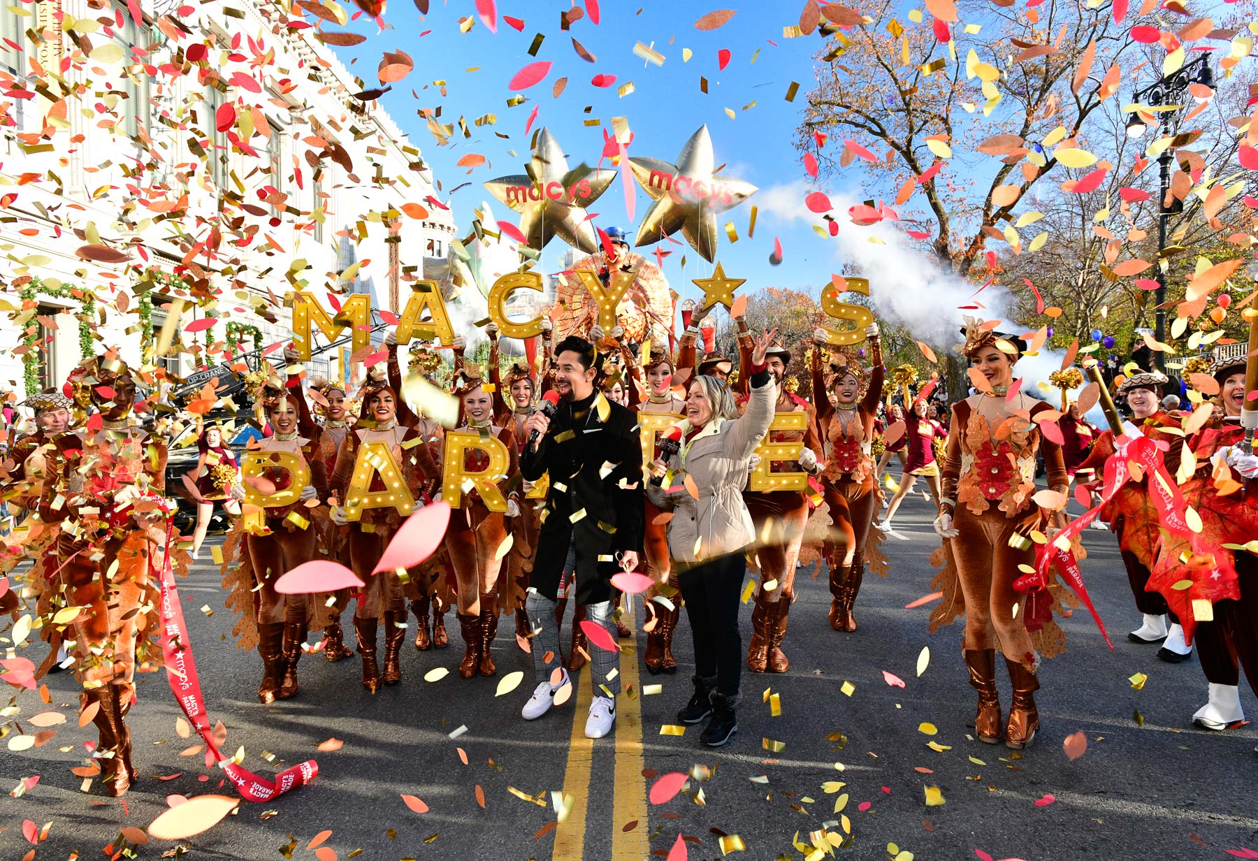 Performers in turkey-themed costumes march with confetti falling at the Macy's Thanksgiving Day Parade.