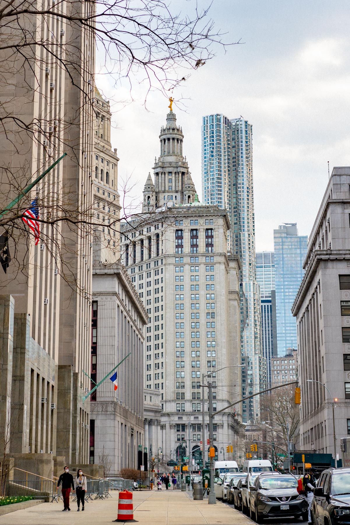 A street view of the Manhattan Municipal Building framed by courthouse buildings and skyscrapers in the Financial District.