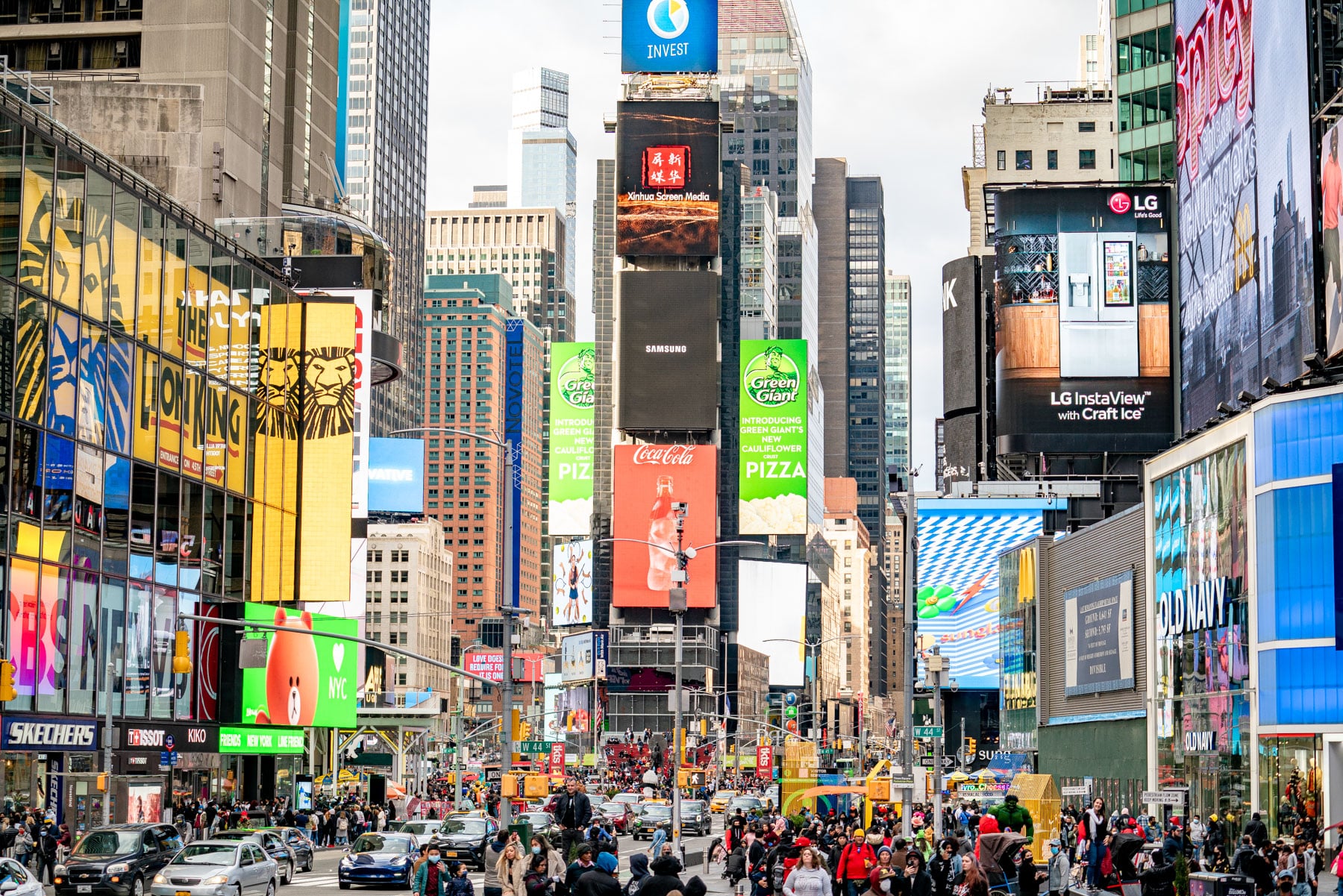 Crowds and traffic fill Times Square beneath large digital billboards.
