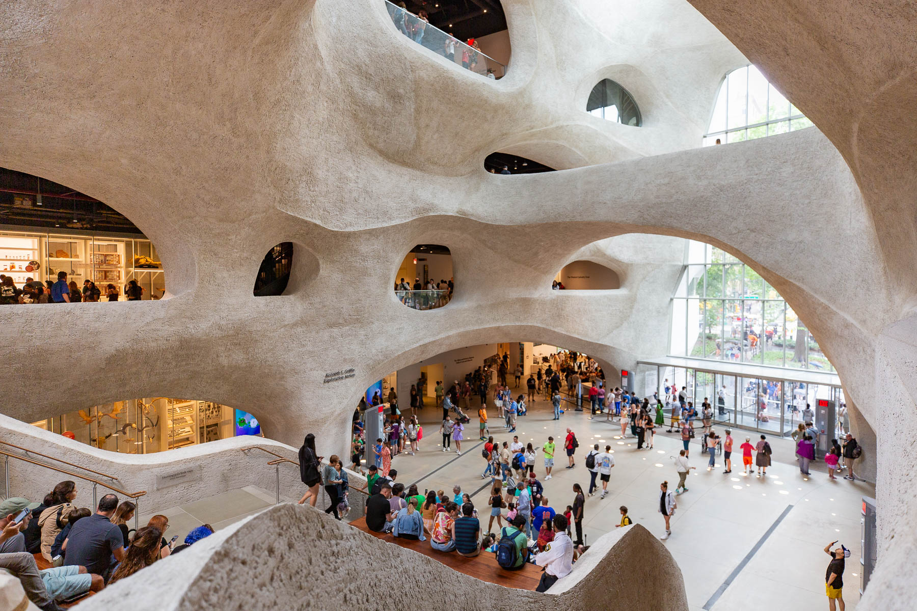 Visitors move through the cave-like curved atrium of a museum's new wing.