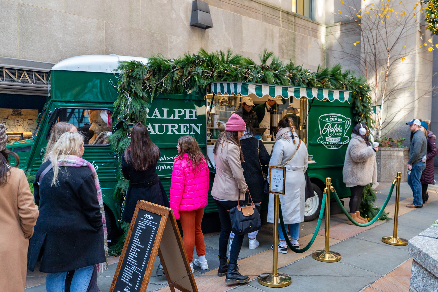 People line up at the Ralph's Coffee truck near Rockefeller Center decorated with holiday greenery.