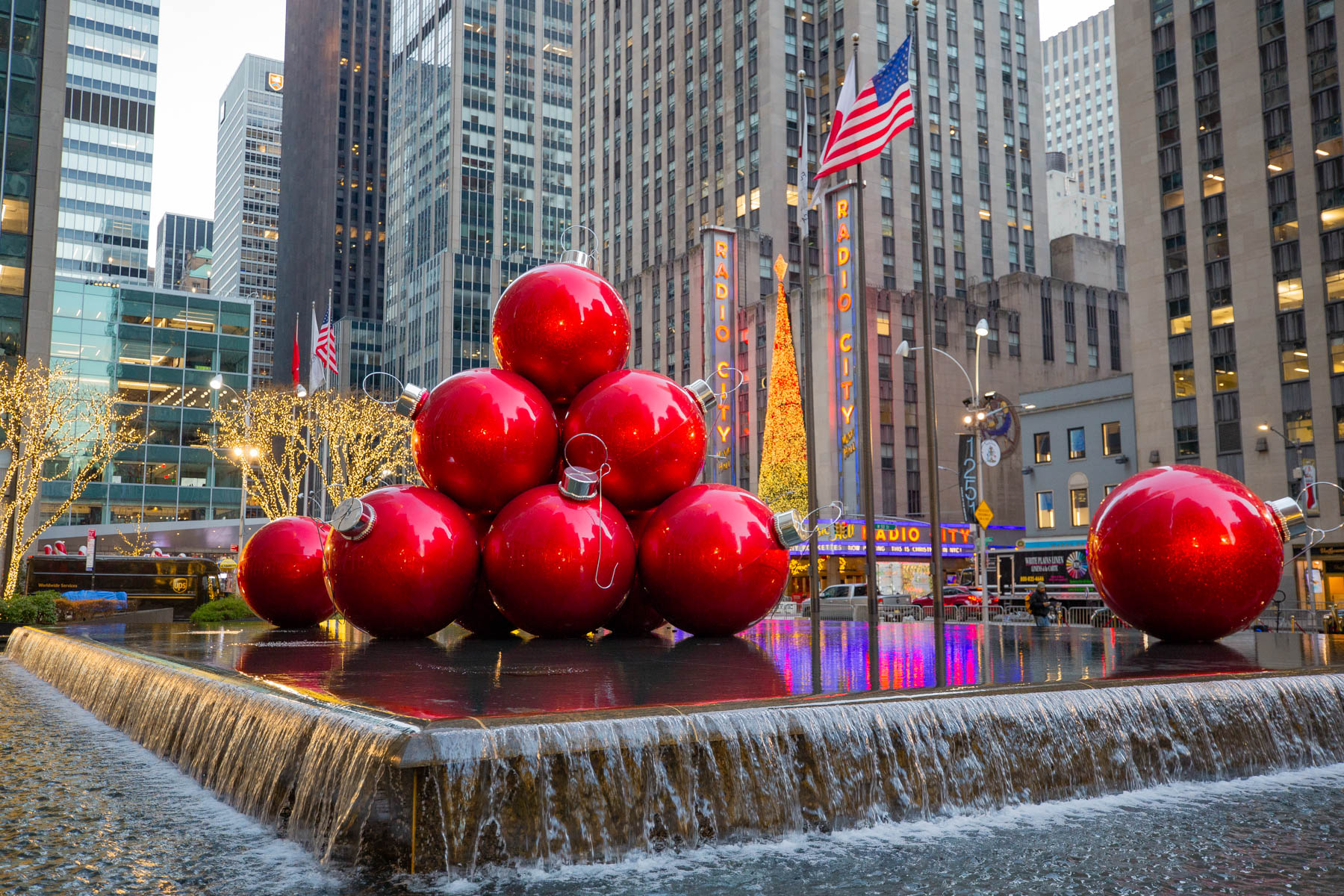 Giant red ornament balls sit atop a fountain near Radio City Music Hall decorated for Christmas.