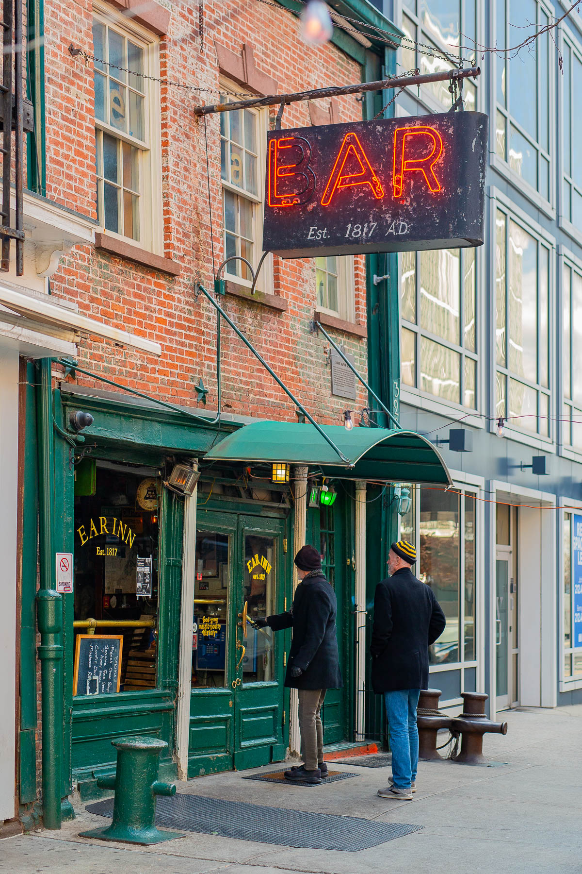 Two people stand outside the Ear Inn beneath its neon bar sign in SoHo.