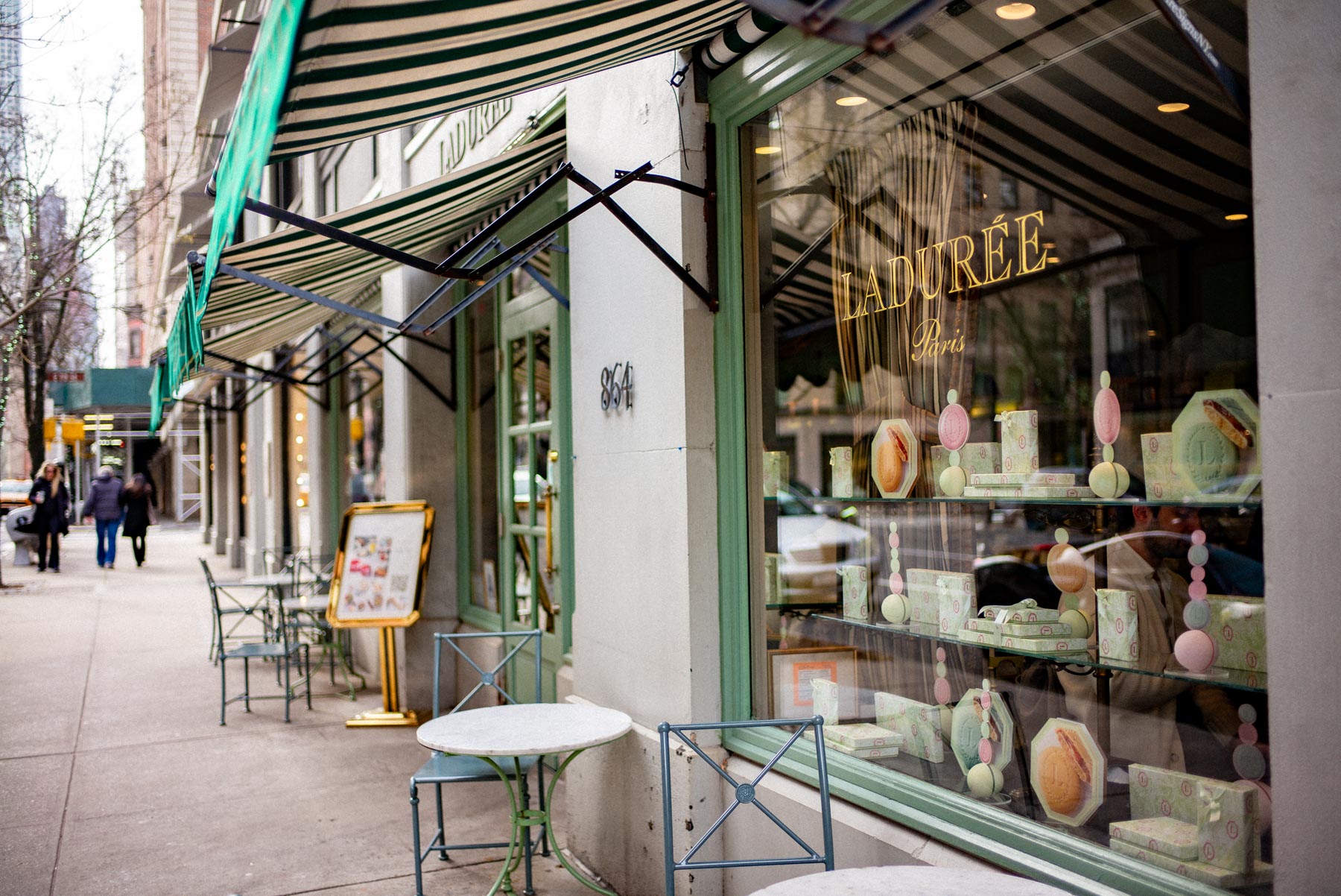 The green-and-white striped storefront of Ladurée bakery on an Upper East Side sidewalk.