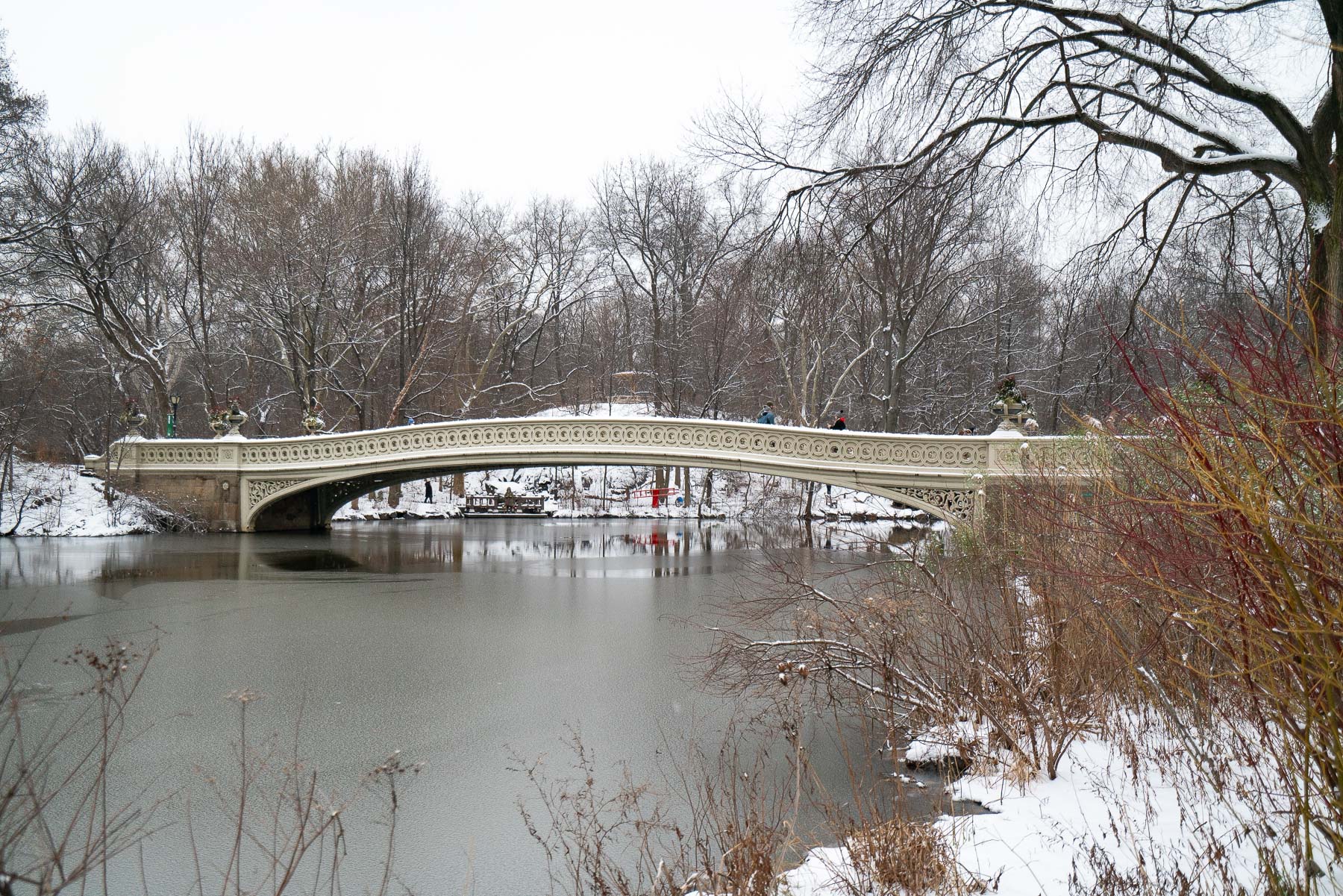 Bow Bridge spans a partially frozen lake in Central Park under snow