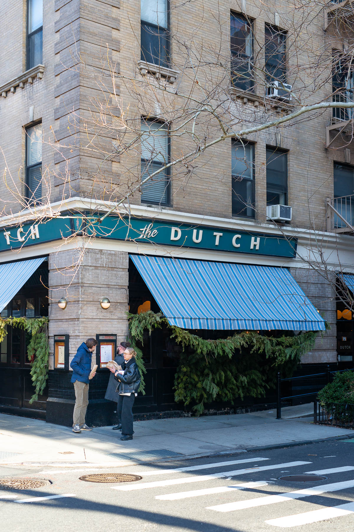 Two people stand outside The Dutch restaurant on a SoHo corner.