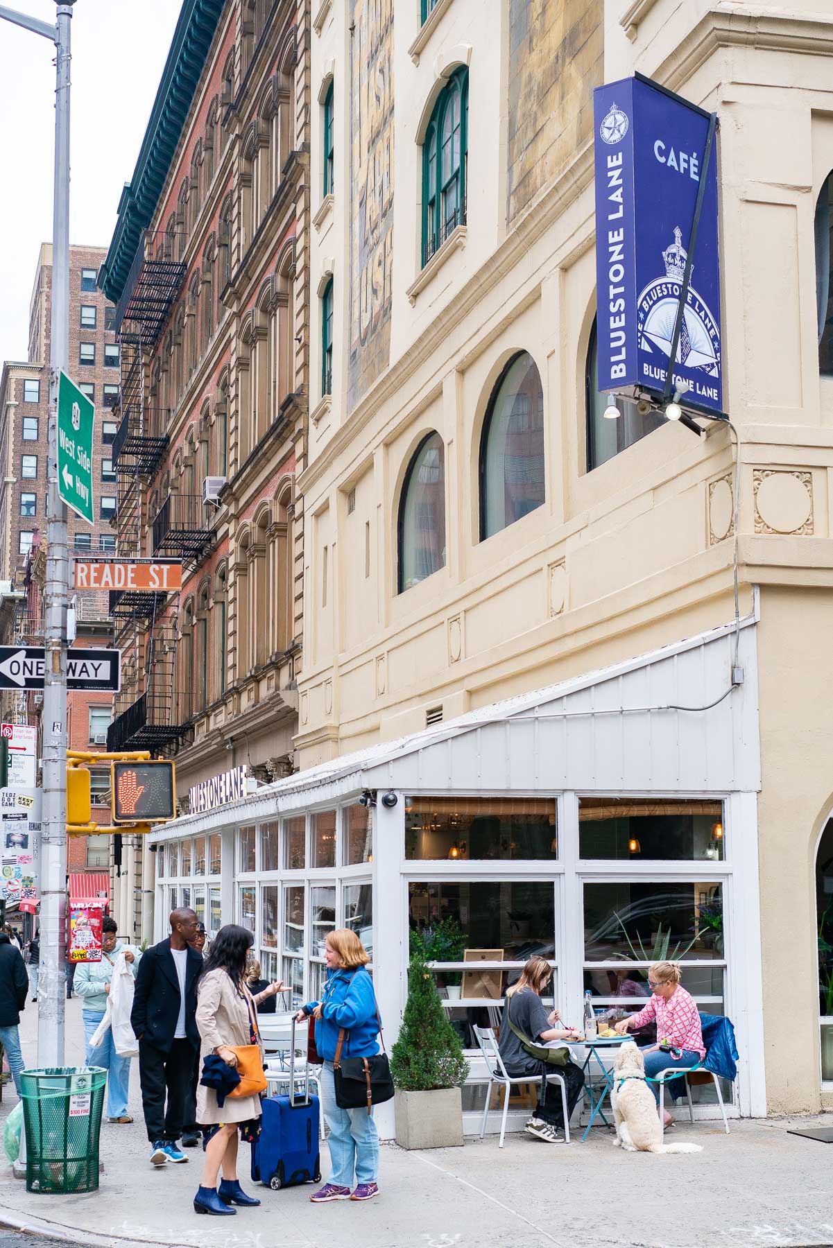 A street corner cafe with a Bluestone Lane sign and outdoor seating in Tribeca.