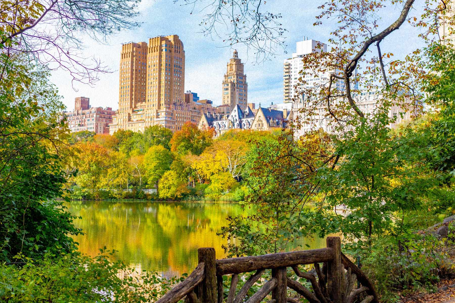 A view across The Lake in Central Park toward the San Remo and Beresford buildings on Central Park West, framed by fall foliage.