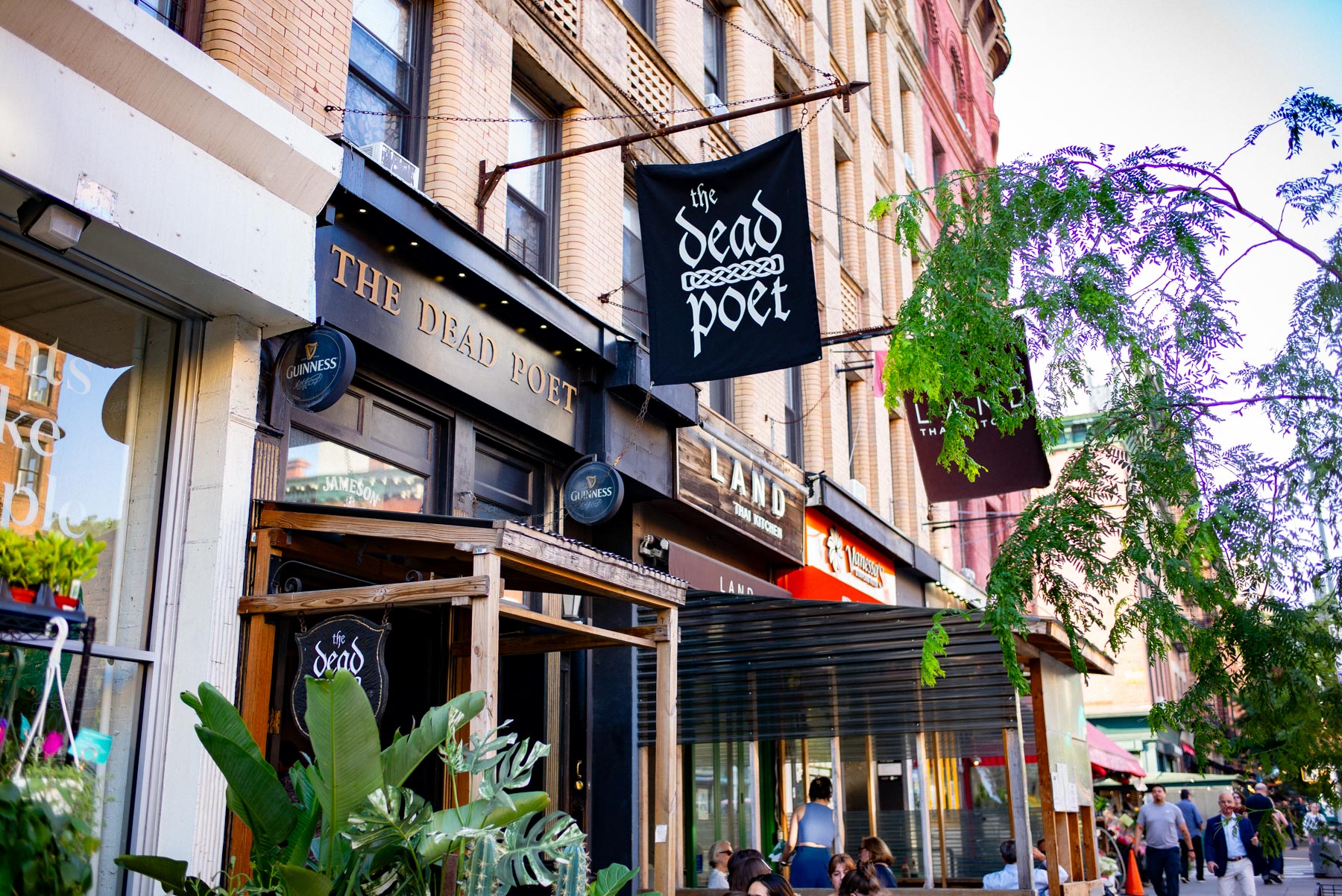 A row of storefronts on the Upper West Side includes The Dead Poet pub and Land Thai Kitchen.