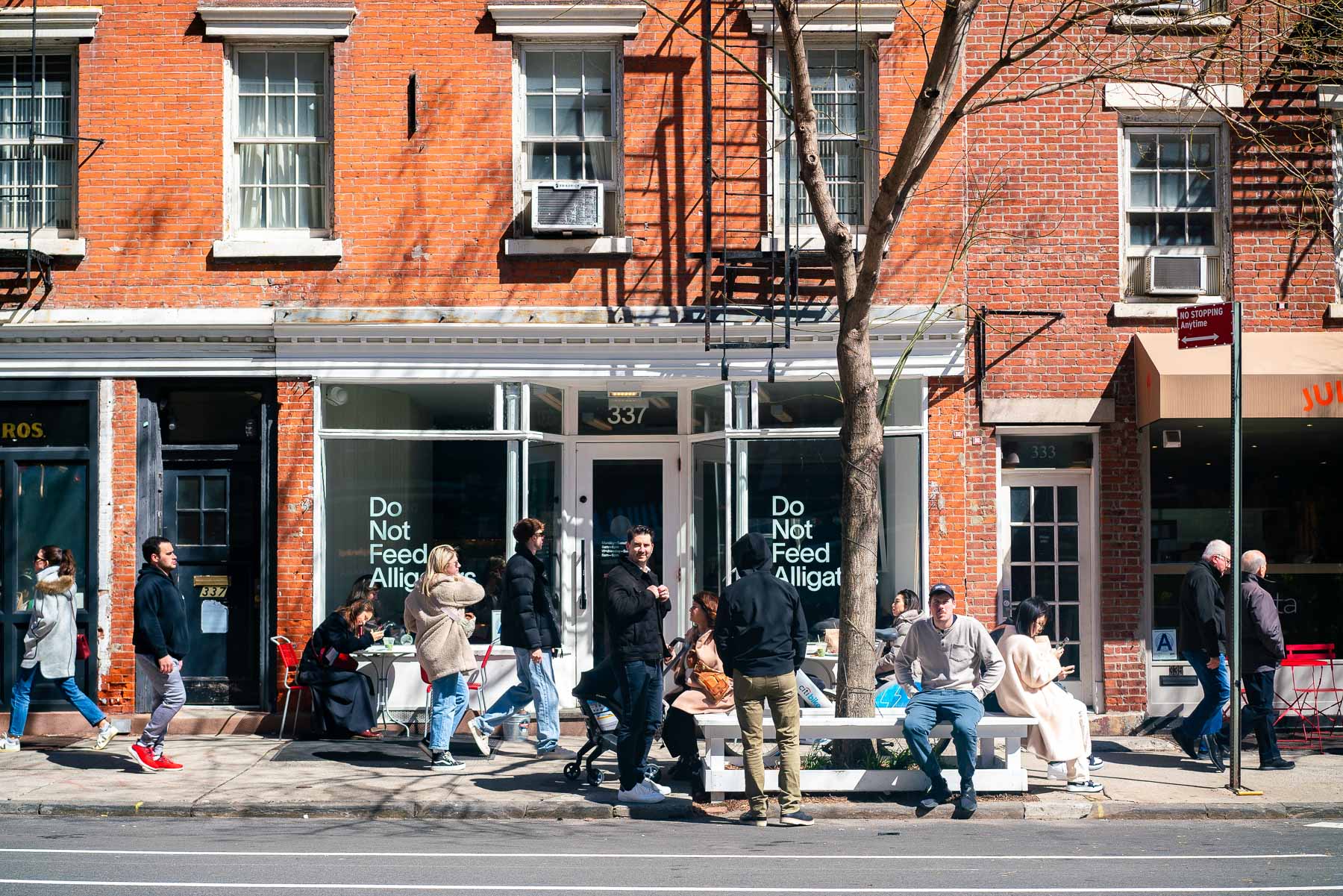 People sitting and hanging out, outside of Do Not Feed the Alligators in NYC