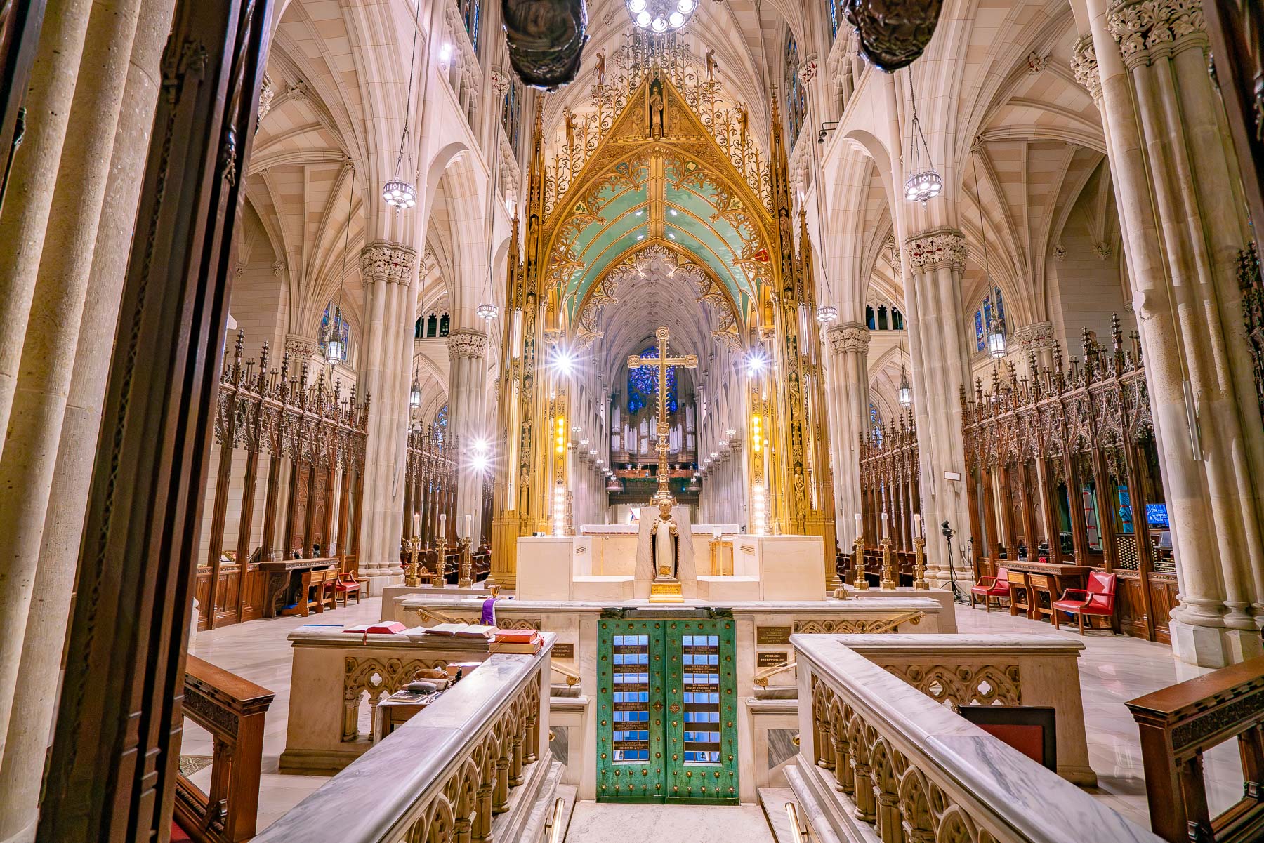 The gilded altar and Gothic nave of St. Patrick's Cathedral are viewed from behind the sanctuary railing.