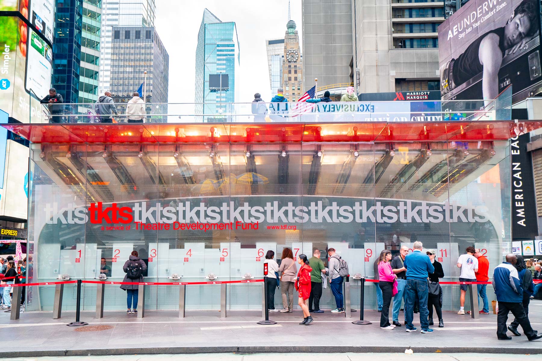 People wait in line at the red glass TKTS ticket booth in Times Square.
