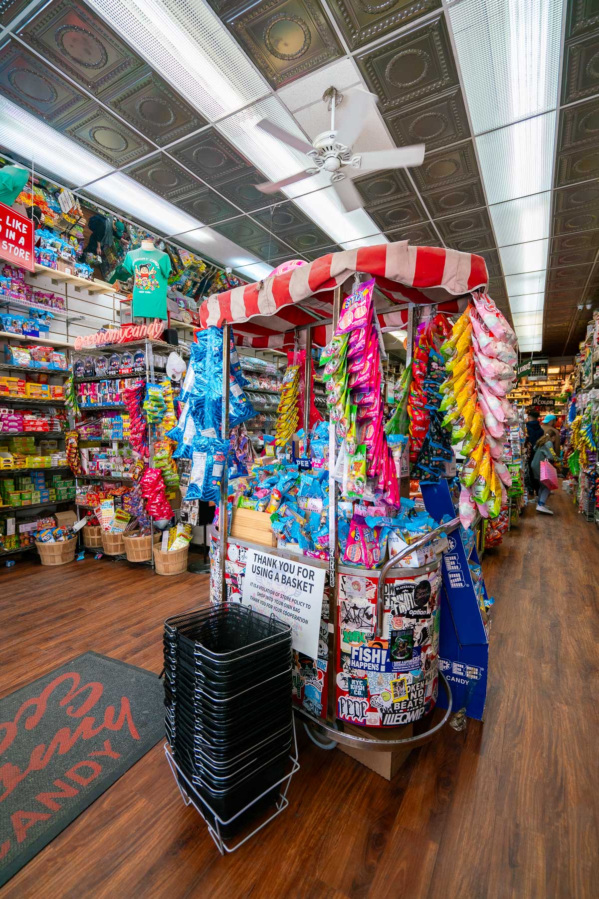 Interior of Economy Candy store with shelves of candy and a striped display cart.