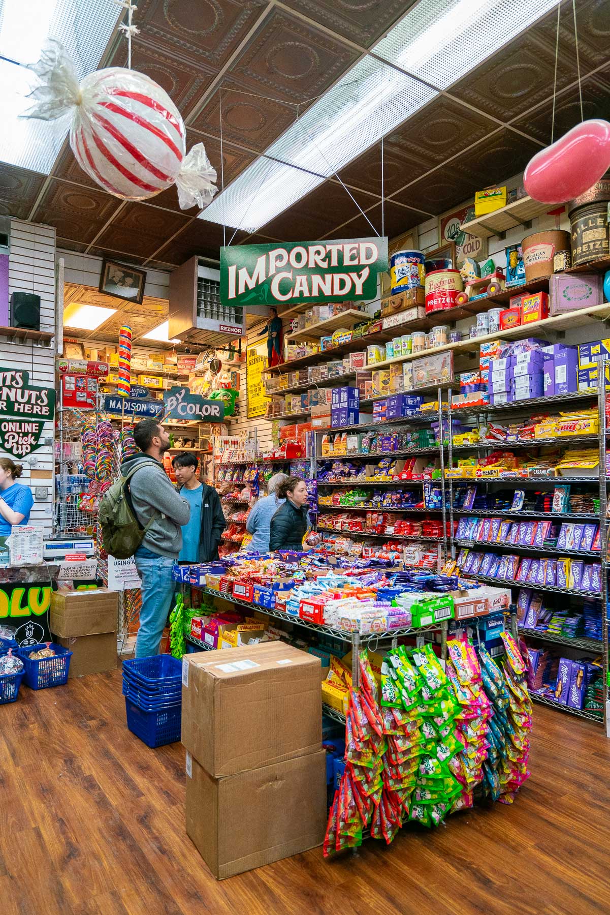 Shoppers browse candy shelves inside a crowded candy store.