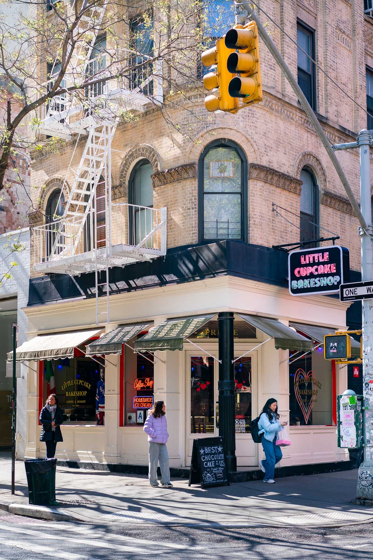 Two young girls and their mother outside of Little Cupcake Bakeshop in Soho during Sunrise