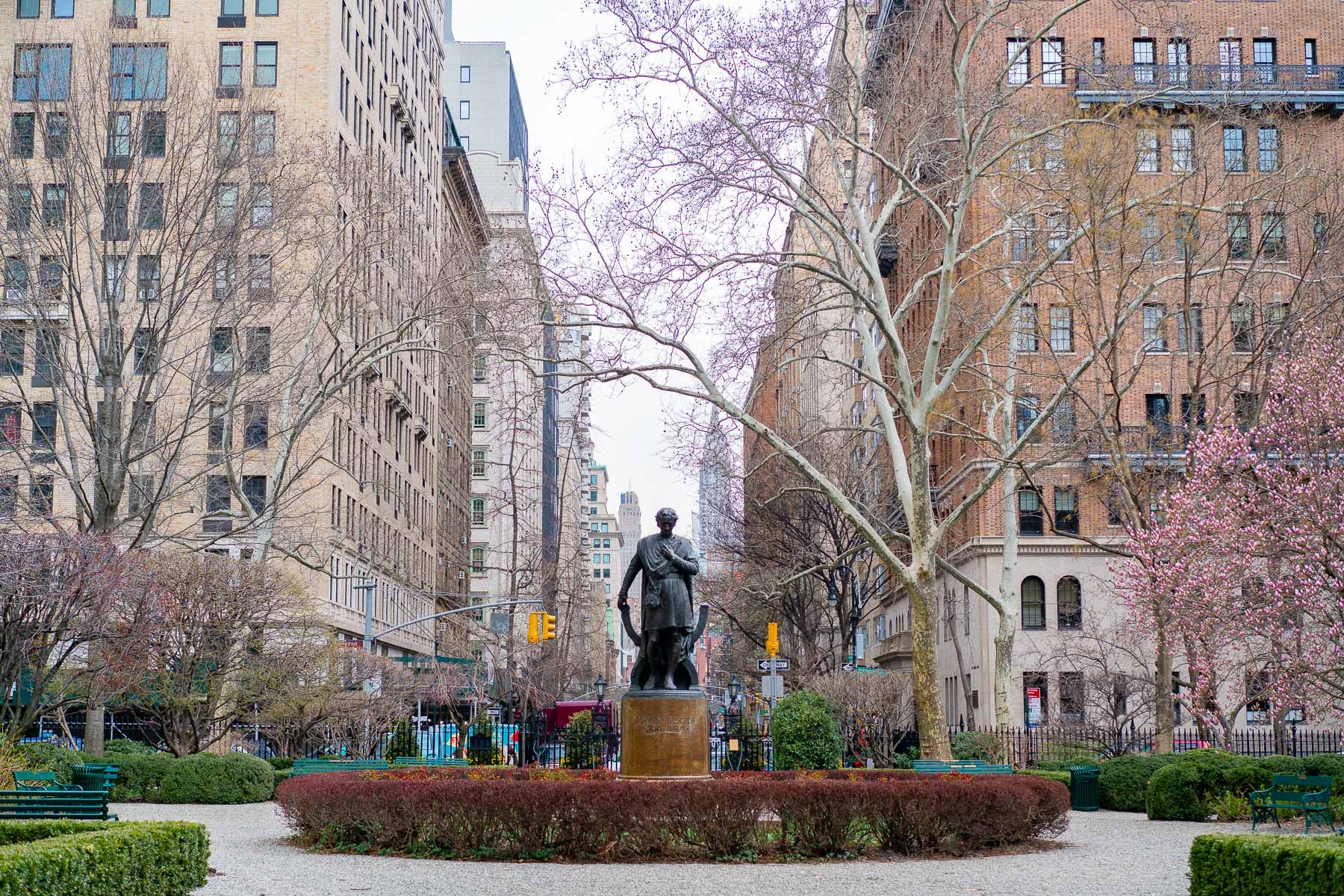 Edwin Booth statue in Gramercy Park surrounded by budding cherry blossom trees in the beginning of spring