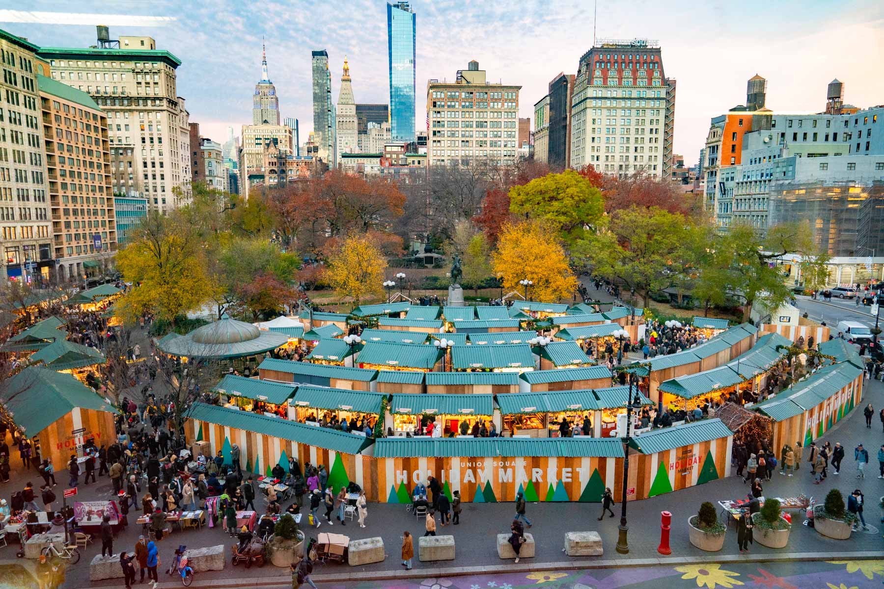 Manhattan skyline during the fall at Union Square Market. Crowds of people shopping the stalls at the Holiday Market in Union Square 